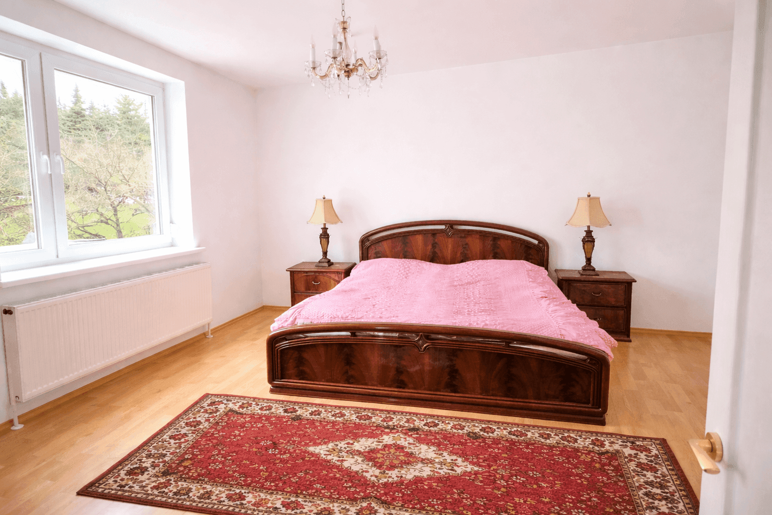 Geräumiges Schlafzimmer mit Doppelbett, Holzfußboden und Kronleuchter, hell und freundlich.