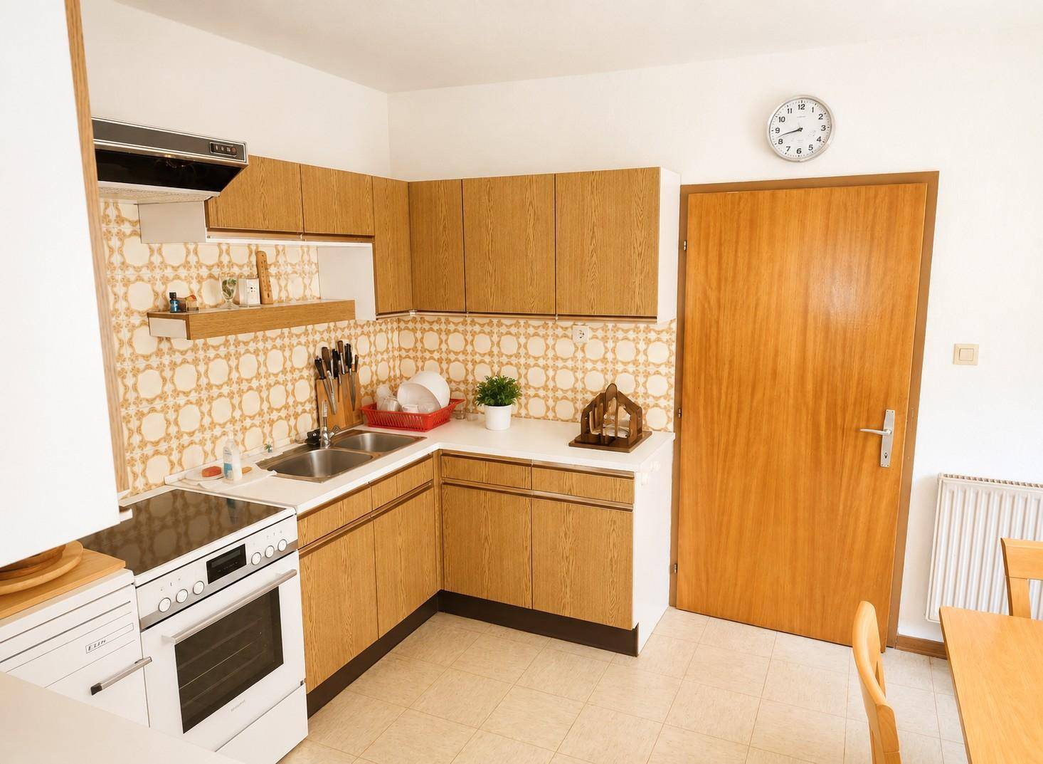 Küche im traditionellen Stil mit Holzschränken, gemusterter Tapete und weißem Herd.