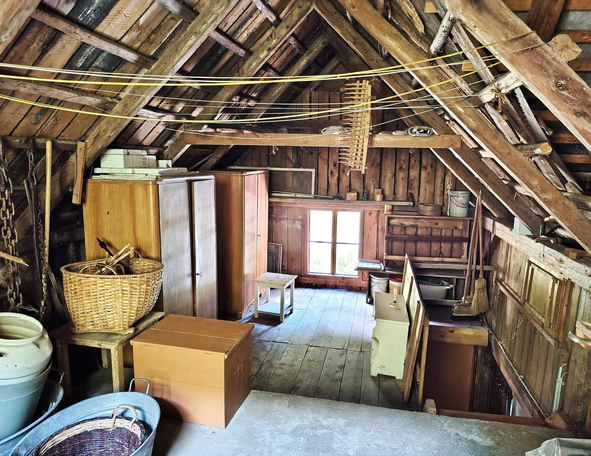 Geräumiger Dachboden mit sichtbaren Holzbalken und gelagerten Gegenständen.