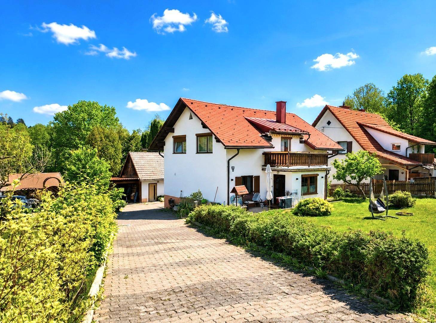 Hausansicht von der Zufahrt mit gepflegtem Garten, Rasen und Hecke.