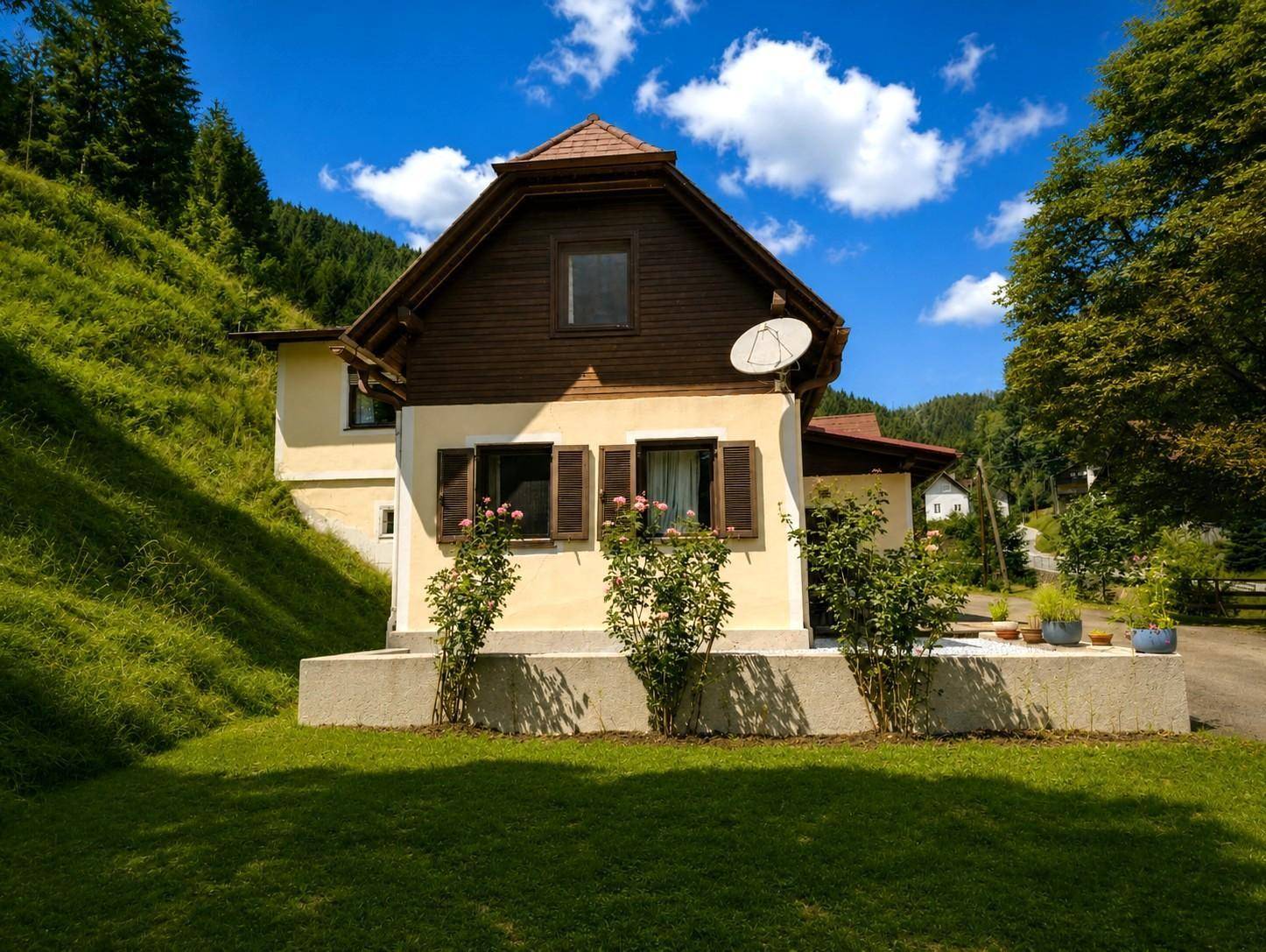 Landhaus mit traditioneller Architektur, umgeben von grünen Hügeln und Rosensträuchern.