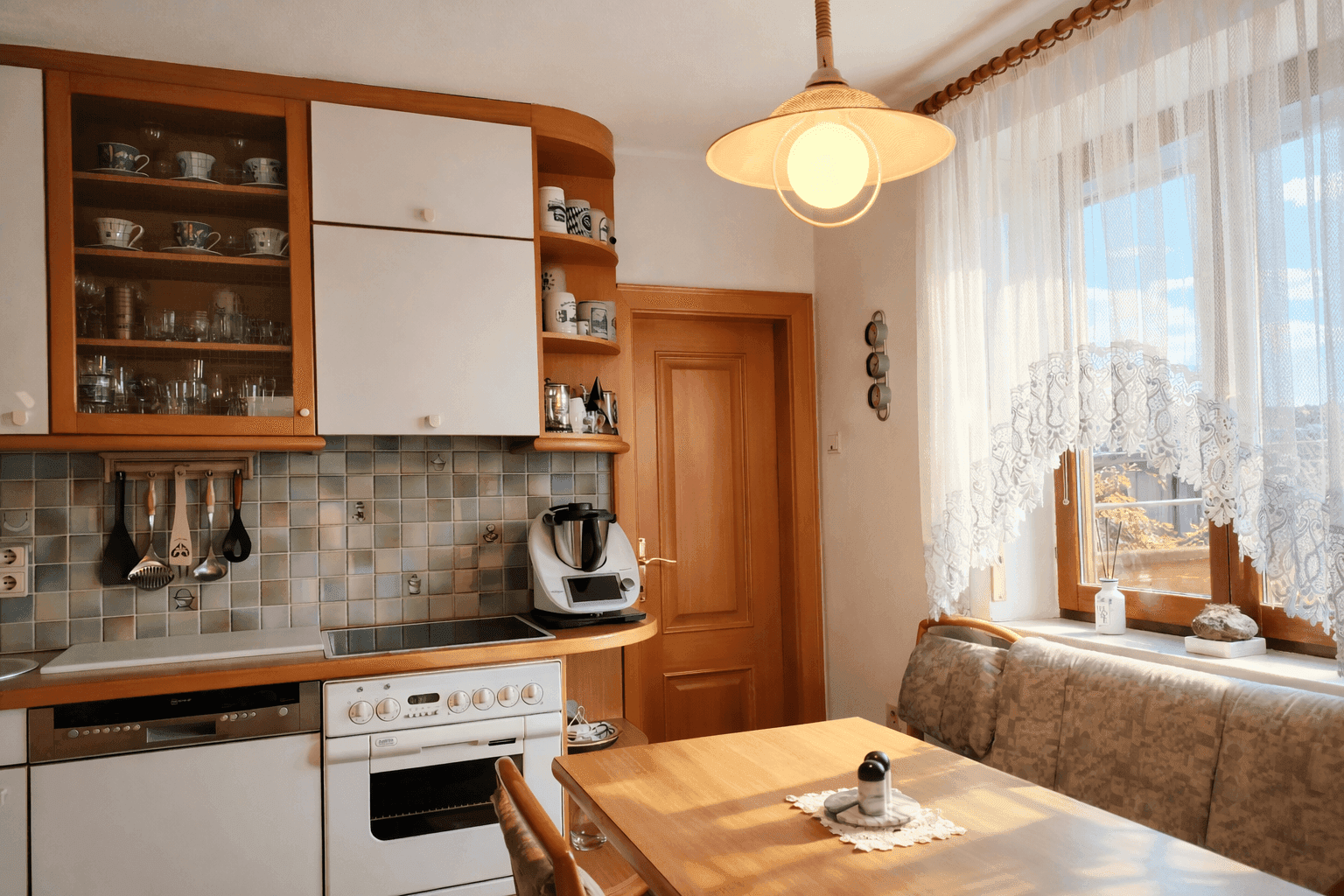 Gemütliche Wohnküche mit Essbereich am Fenster, Holzmöbeln und integrierten Geräten.