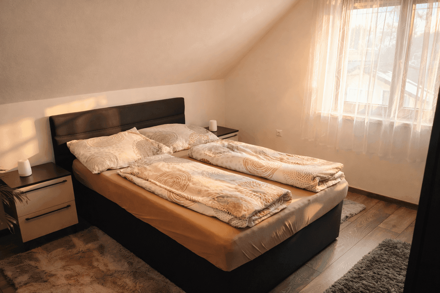 Helles Schlafzimmer im Dachgeschoss mit Doppelbett, Holzboden und viel Tageslicht.