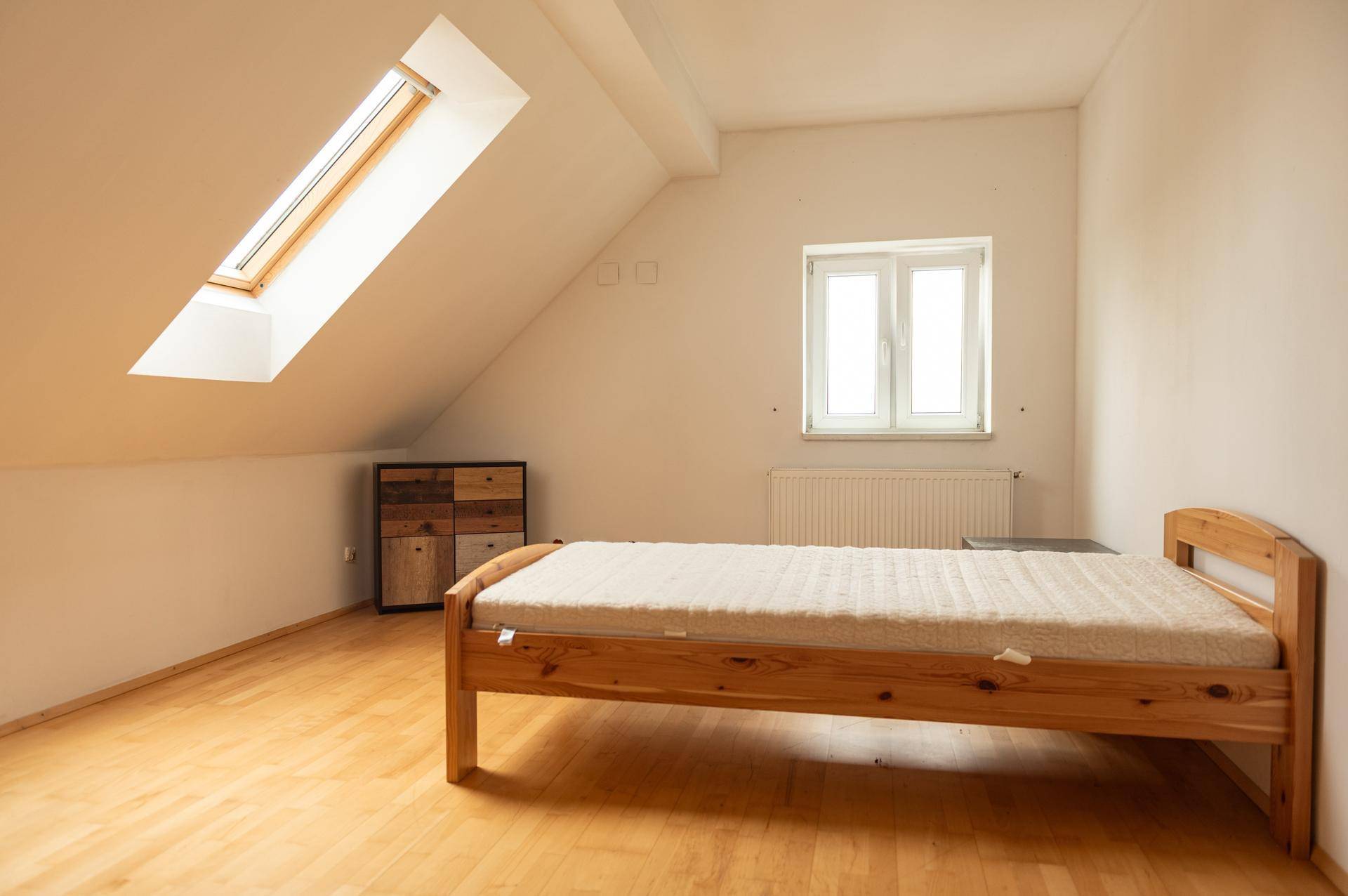 Helles Schlafzimmer im Dachgeschoss mit Holzboden, Dachfenster und einem Einzelbett.