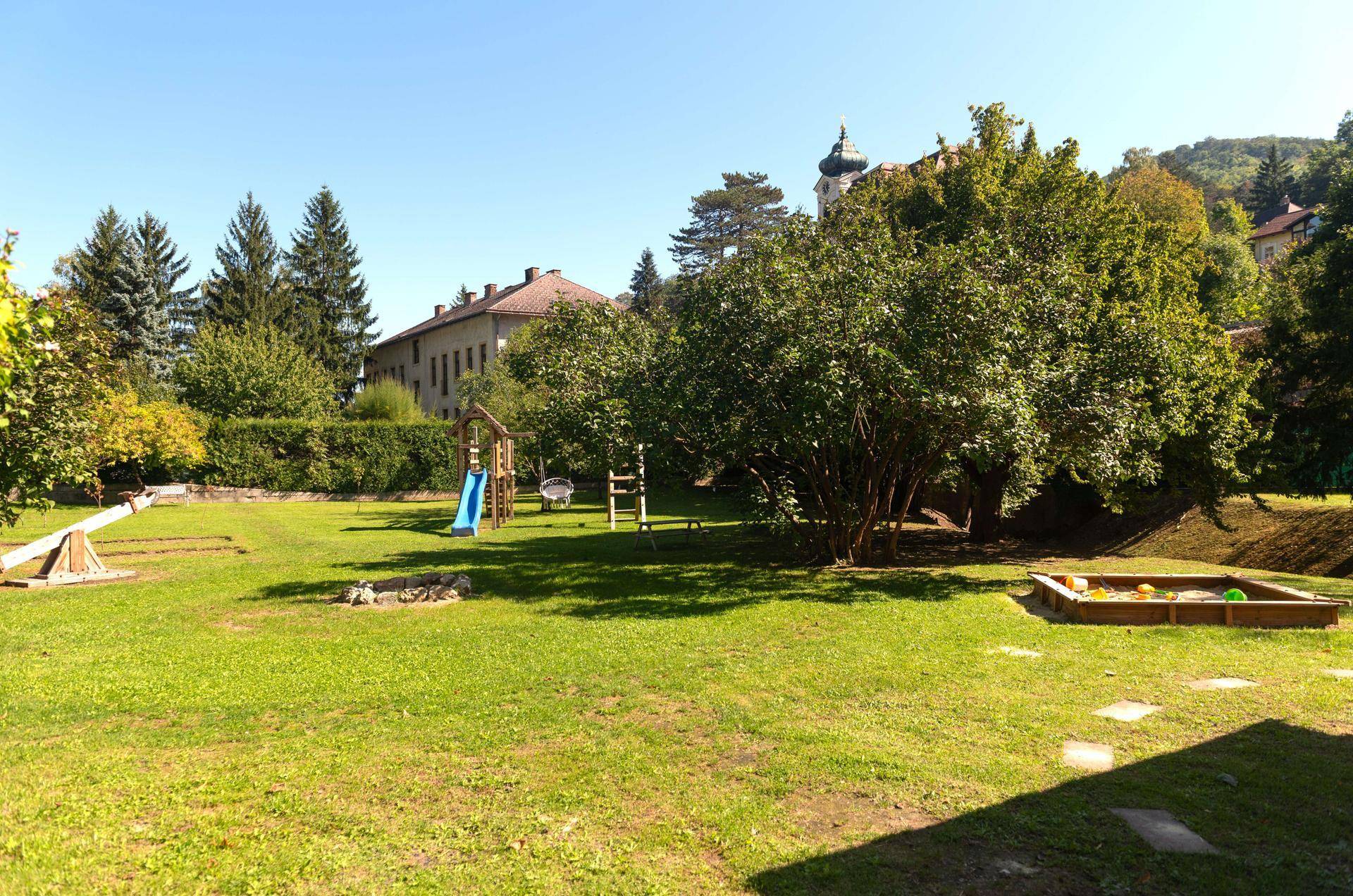 Großer Garten mit Spielplatz, Sandkasten und viel Grünfläche, ideal für Kinder.