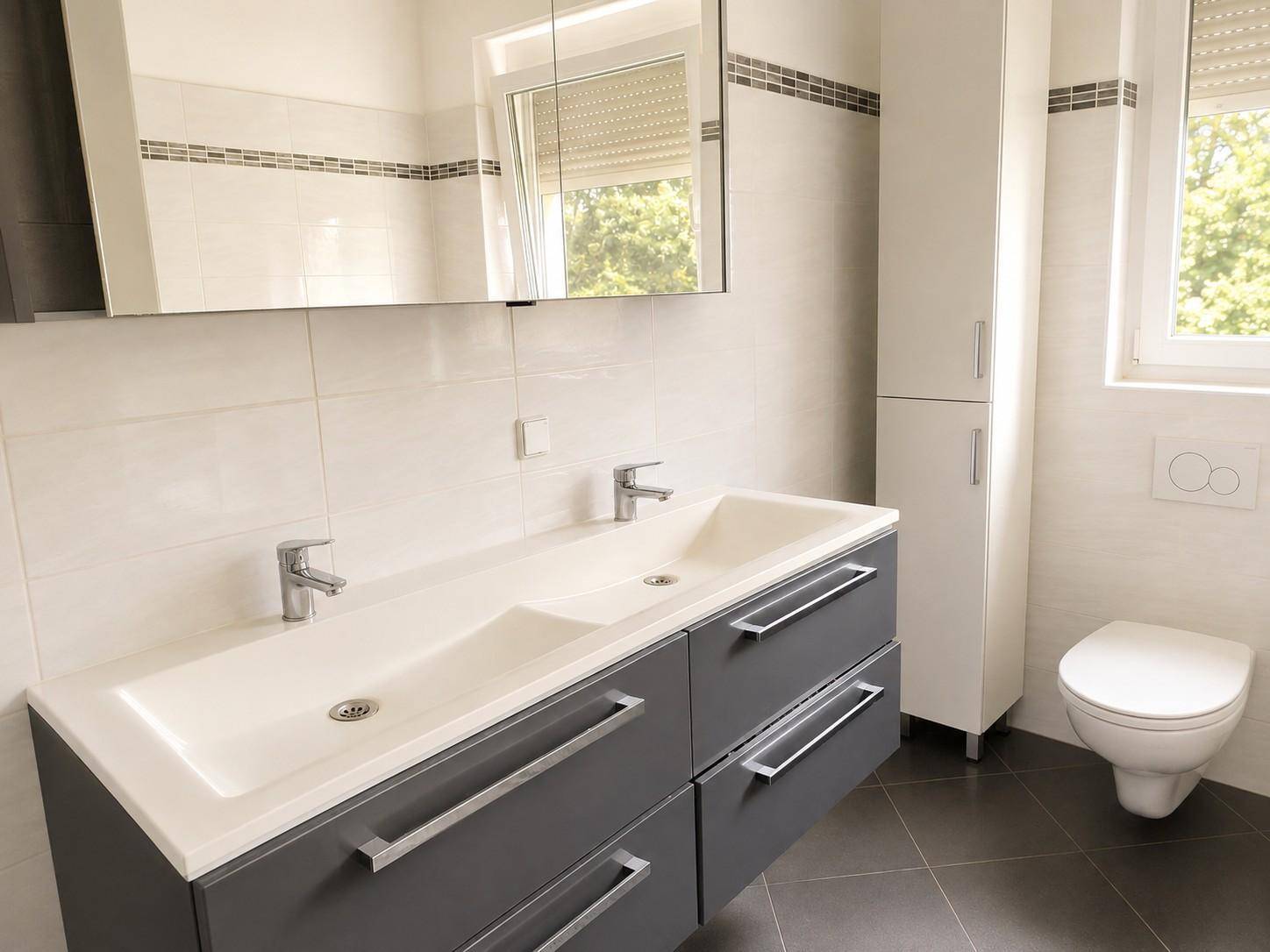 Modernes Badezimmer mit Doppelwaschbecken, Spiegelschrank und Wand-WC.