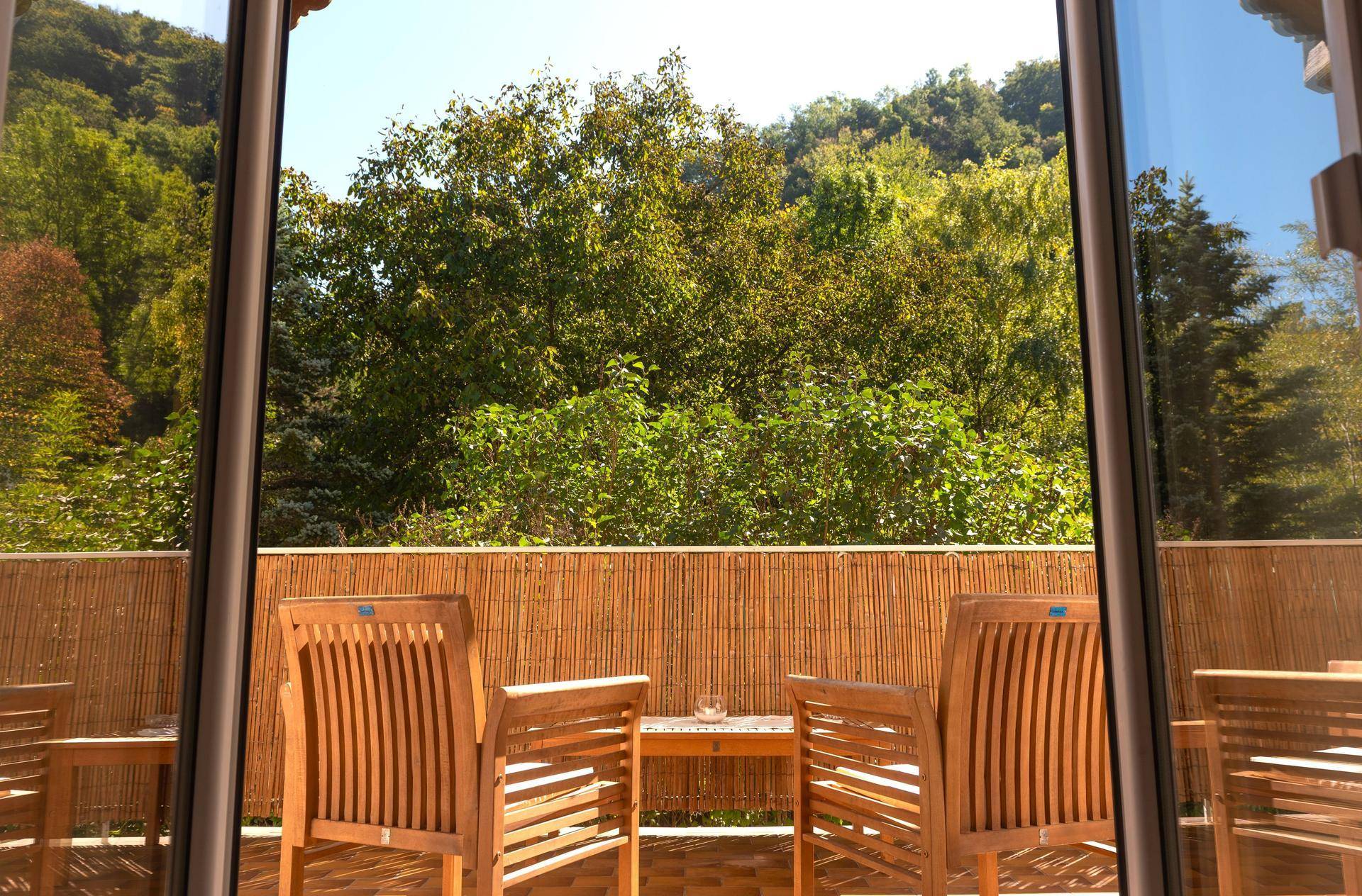 Balkon mit Holzsitzmöbeln und Blick auf die umliegende grüne Hügellandschaft.