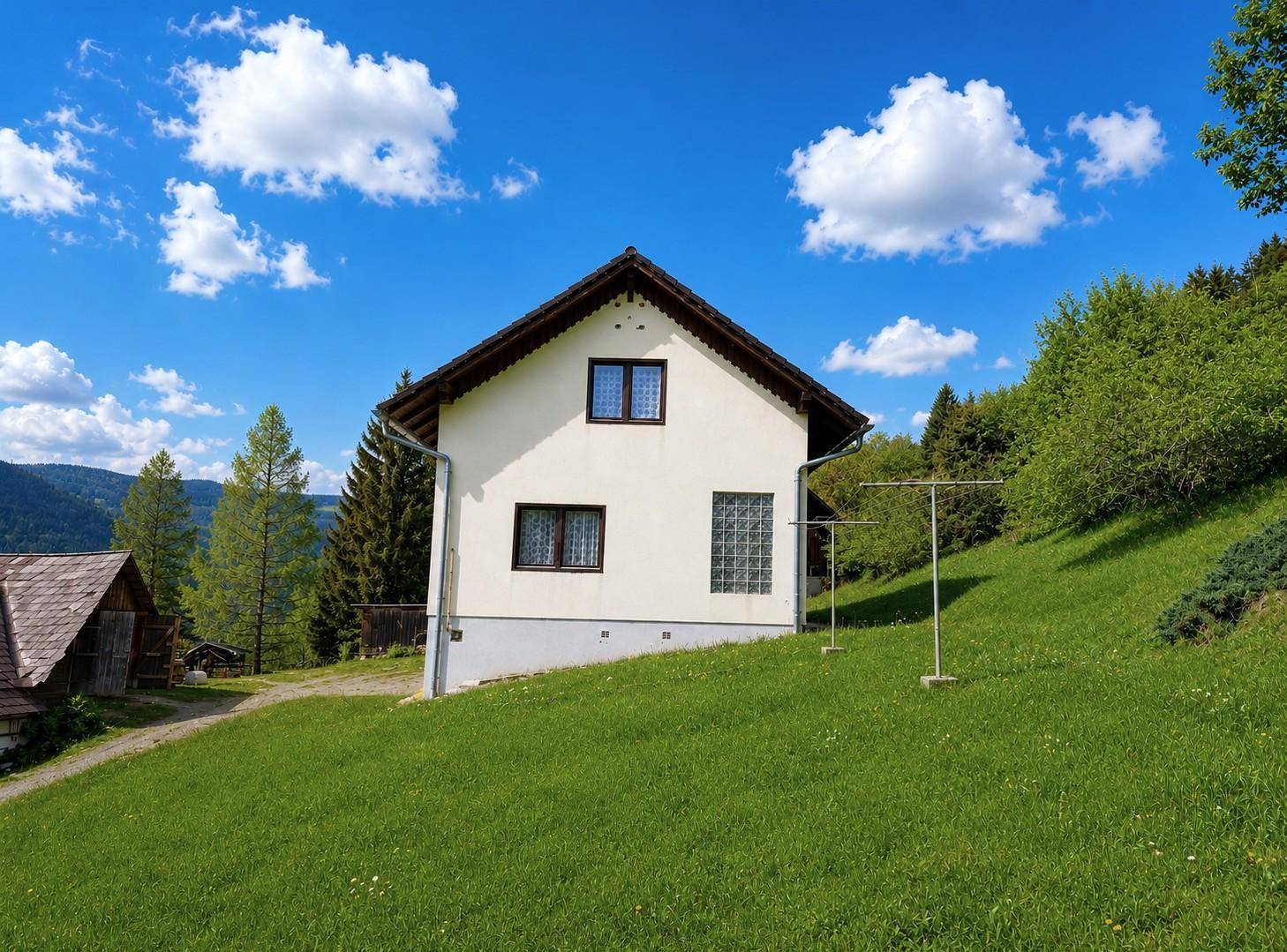 Freistehendes Einfamilienhaus mit weißer Fassade und Satteldach auf einem grünen Grundstück.