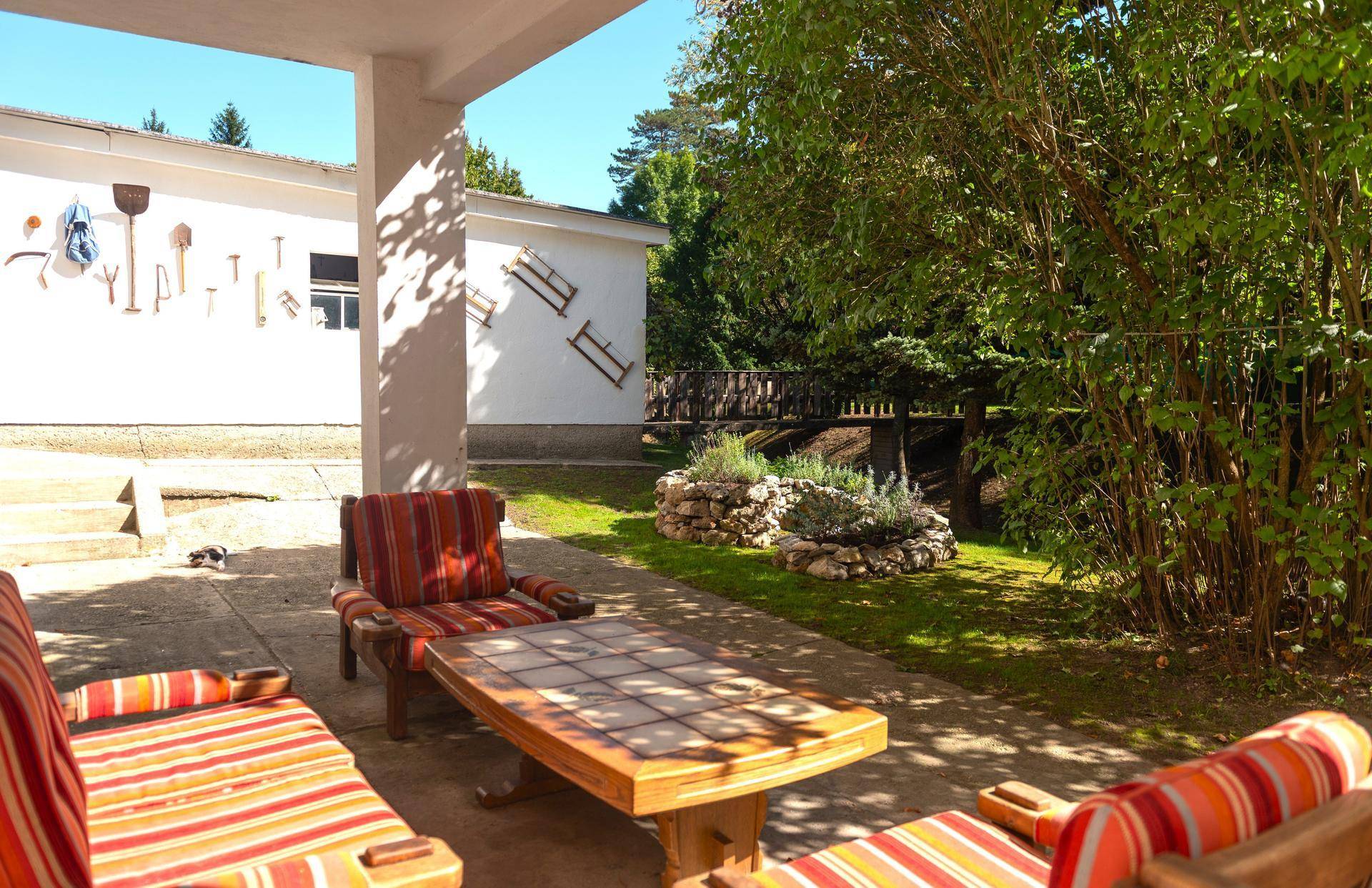 Überdachte Terrasse mit rustikalen Sitzmöbeln und Blick auf den Garten und die Umgebung.
