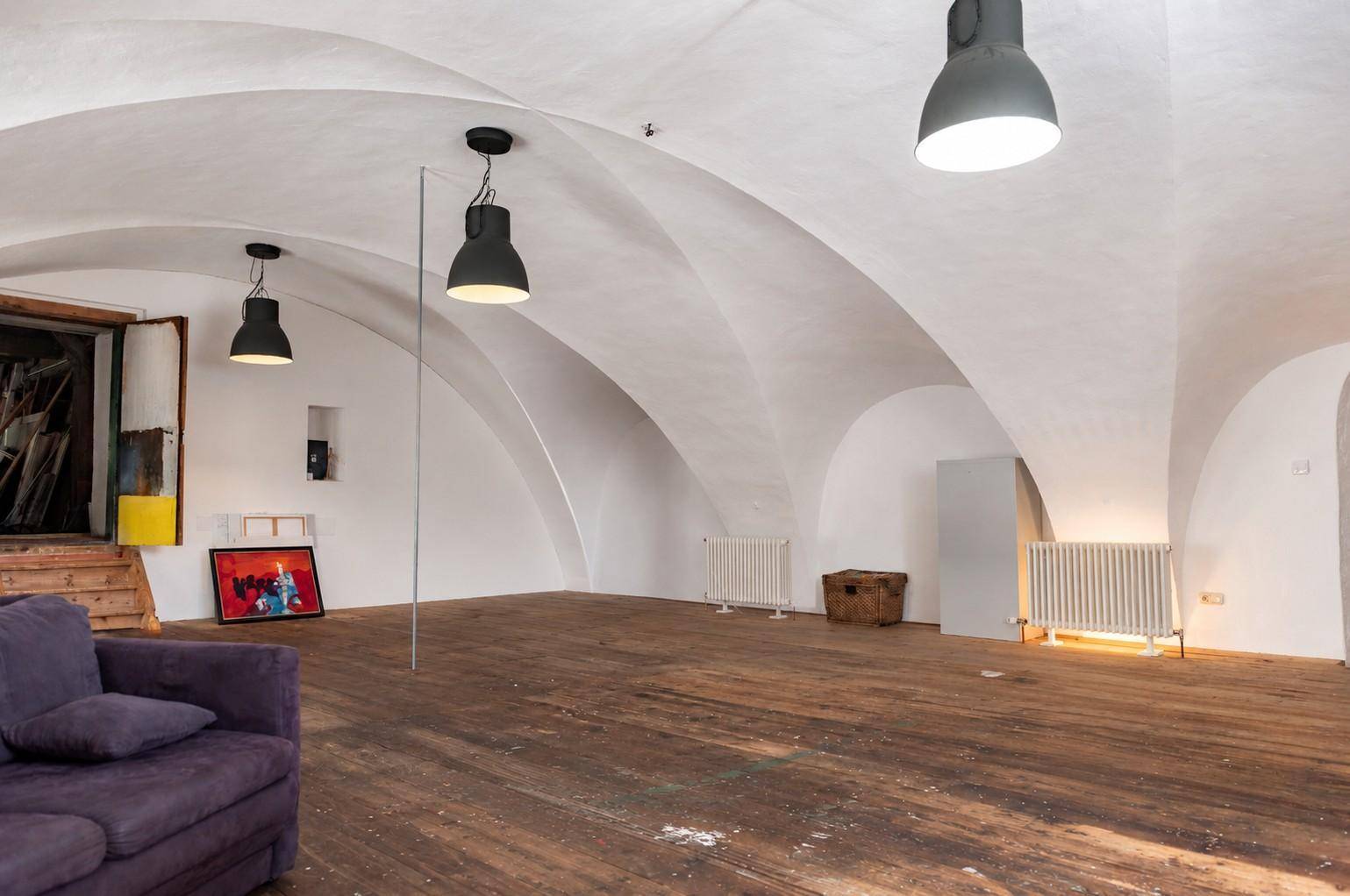 Geräumiger Wohnbereich mit eleganten Gewölbedecken, rustikalem Holzboden und moderner Dekoration.