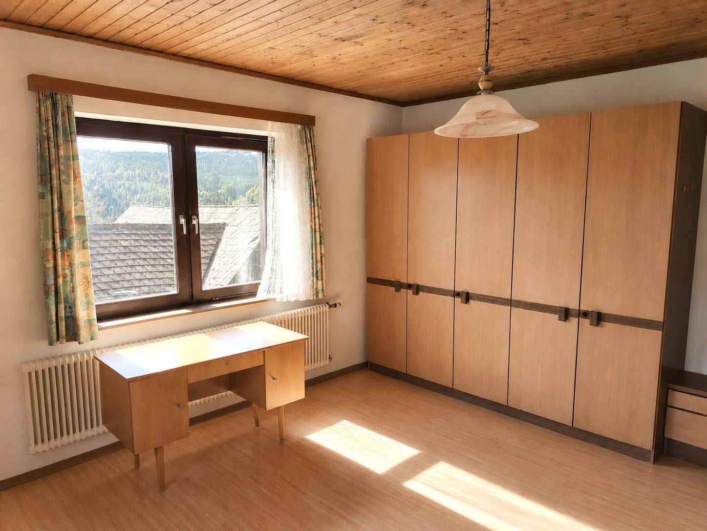 Helles Zimmer mit großem Einbauschrank, Schreibtisch und Blick auf die Dächer und Natur.