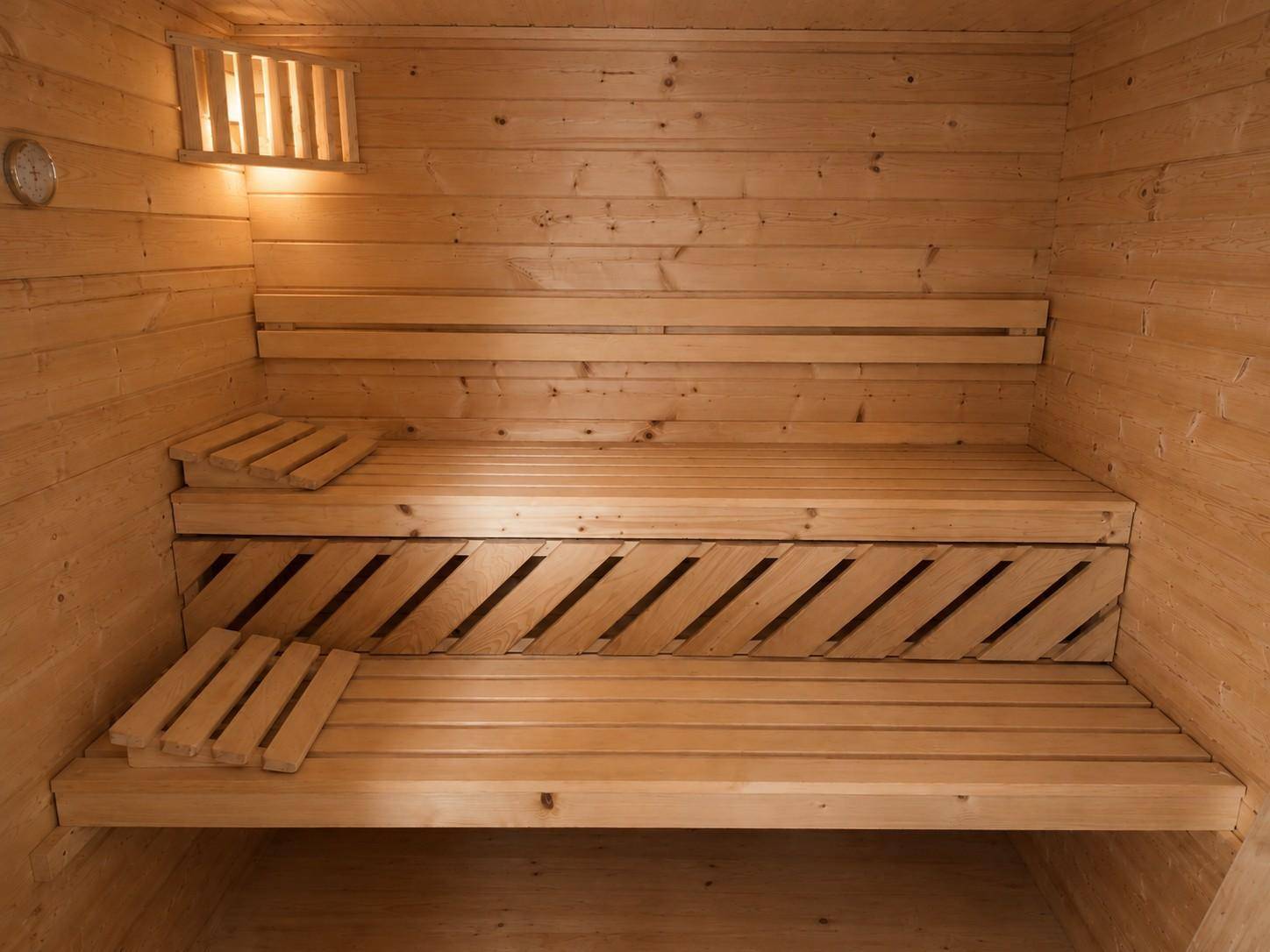 Gemütliche Holzsauna mit mehrstufigen Bänken und indirekter Beleuchtung für Entspannung.