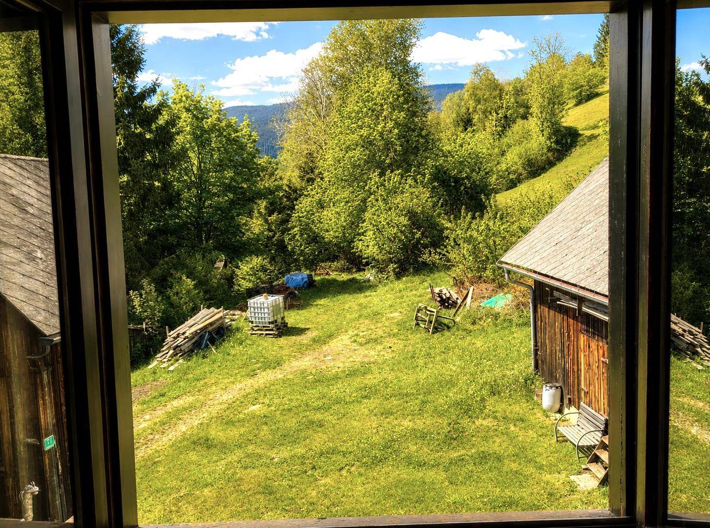 Fensterblick auf das ländliche Grundstück mit Scheune und grüner Wiese.