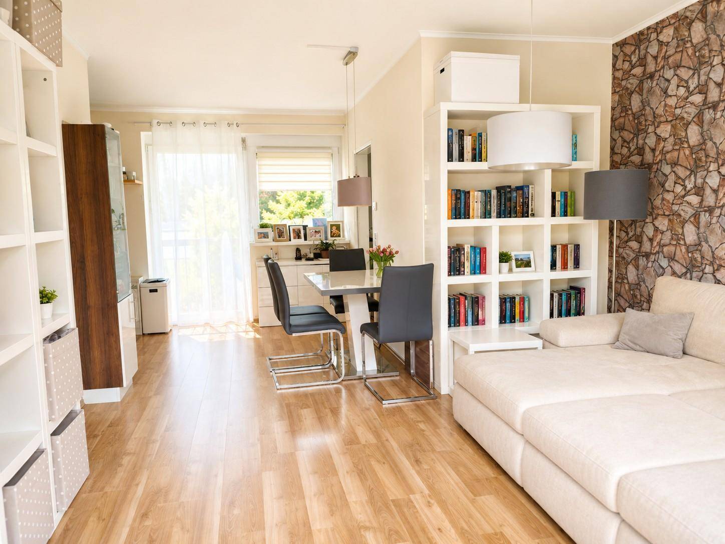 Gemütlicher Wohn-Essbereich mit Holzboden, Sofa und dekorativer Steinwand.
