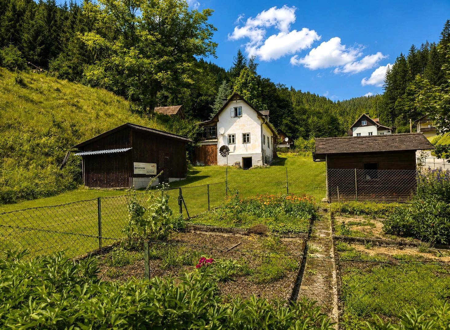 Gartenbereich mit Gemüsegarten, Schuppen und weiteren Häusern in der hügeligen Landschaft.