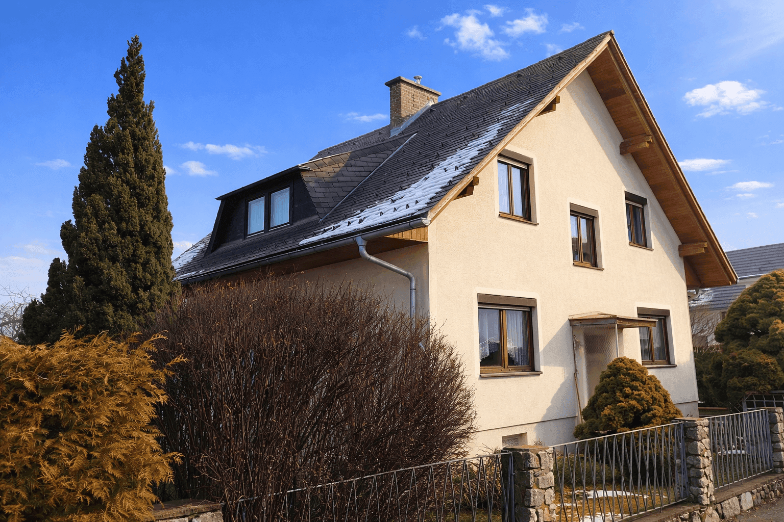 Einfamilienhaus mit Satteldach, Gaubenfenstern und gepflegter Fassade im Winter.