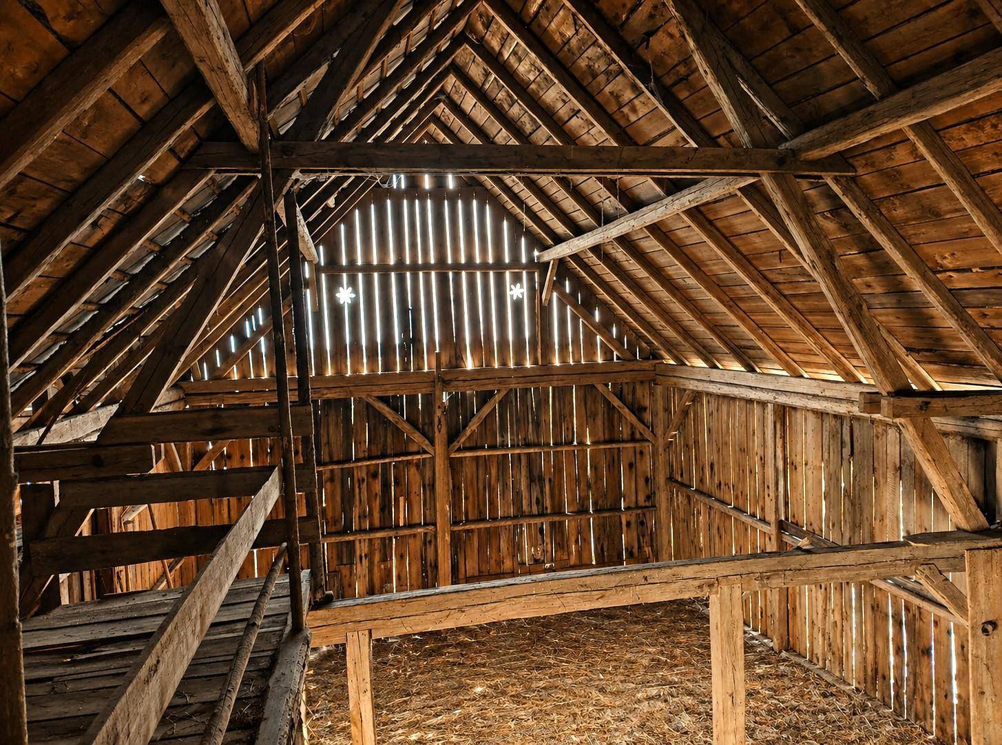 Rustikaler Dachboden oder Scheuneninnenraum mit sichtbaren Holzbalken und viel natürlichem Lichteinfall.