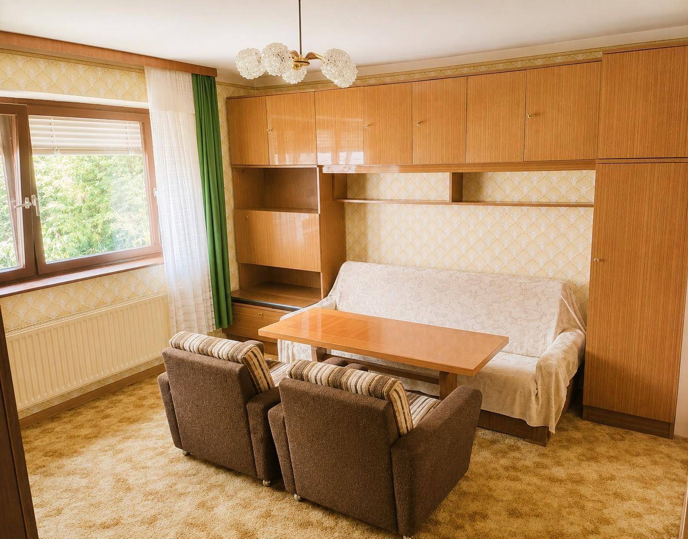 Wohnzimmer mit Schlafsofa, zwei Sesseln und Holzmöbeln im traditionellen Stil.