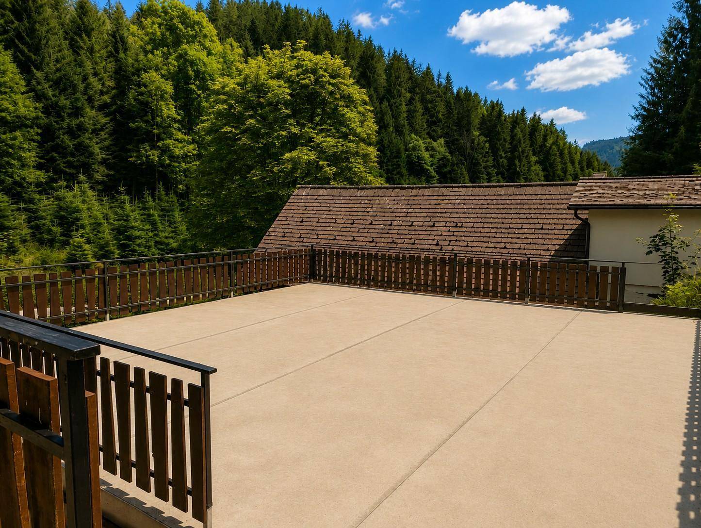 Große, offene Terrasse mit Holzzaun, ideal für Entspannung im Freien.