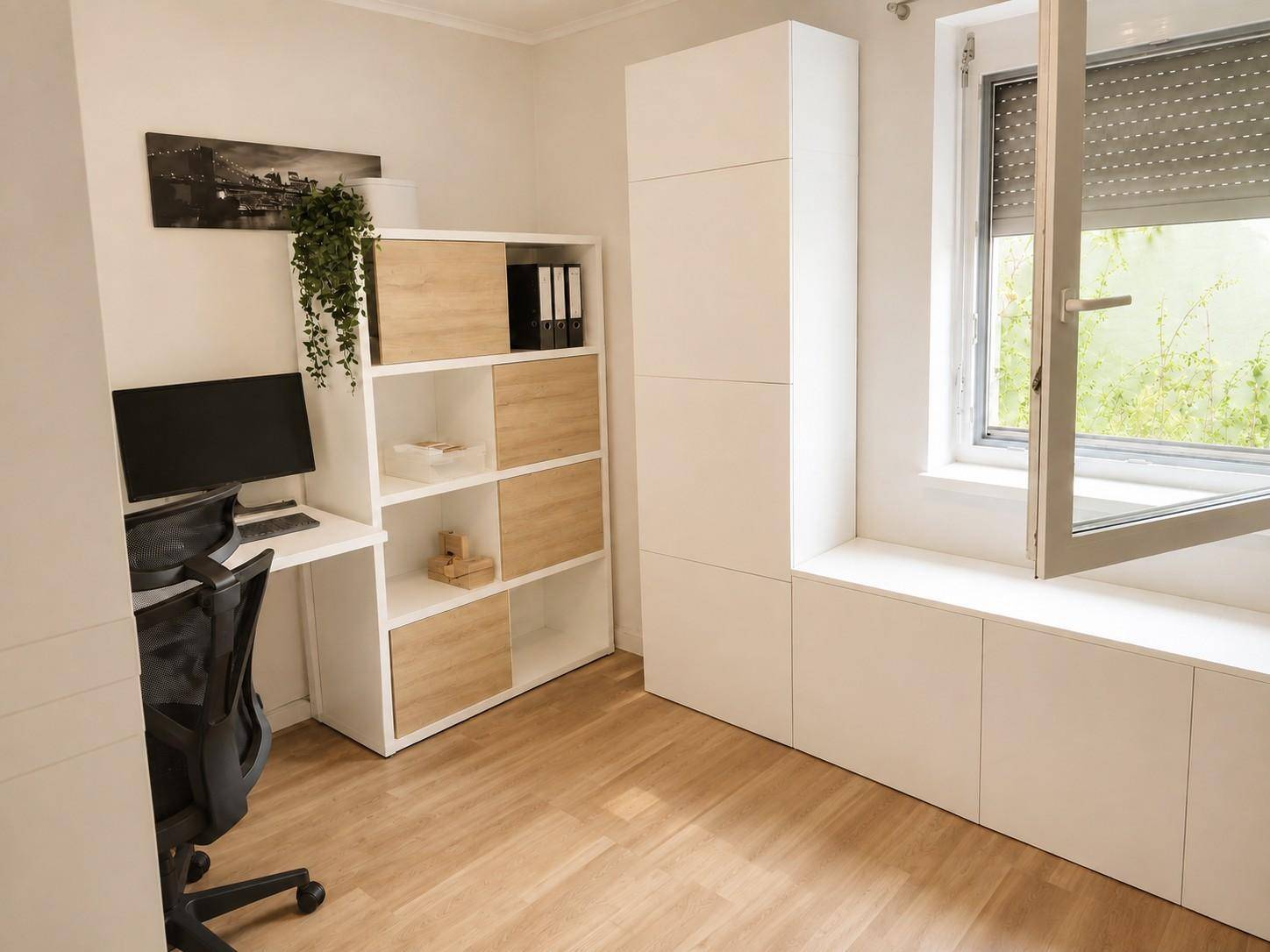 Helles Arbeitszimmer mit Schreibtisch, Regal und Fenster mit Rollladen.