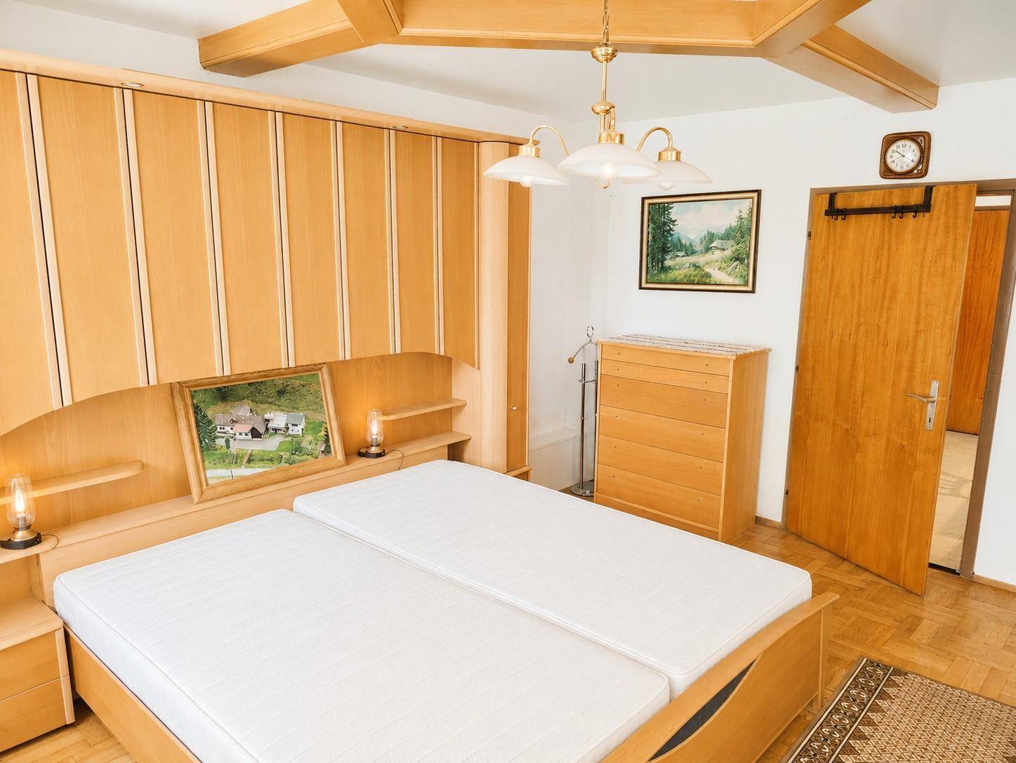 Schlafzimmer mit hellen Holzmöbeln, Einbauschränken und zwei Einzelbetten.
