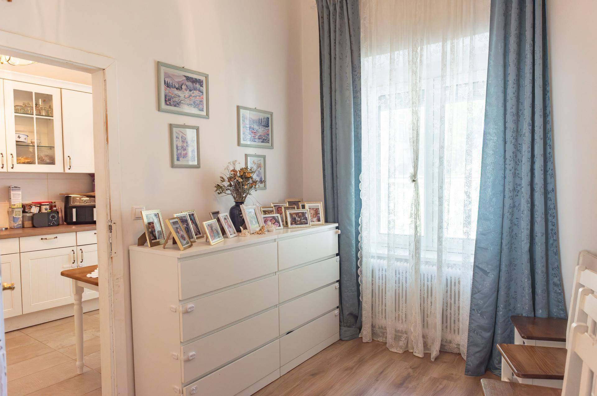 Heller Flur mit Kommode und Fenster, der zur Küche führt, mit Holzboden.