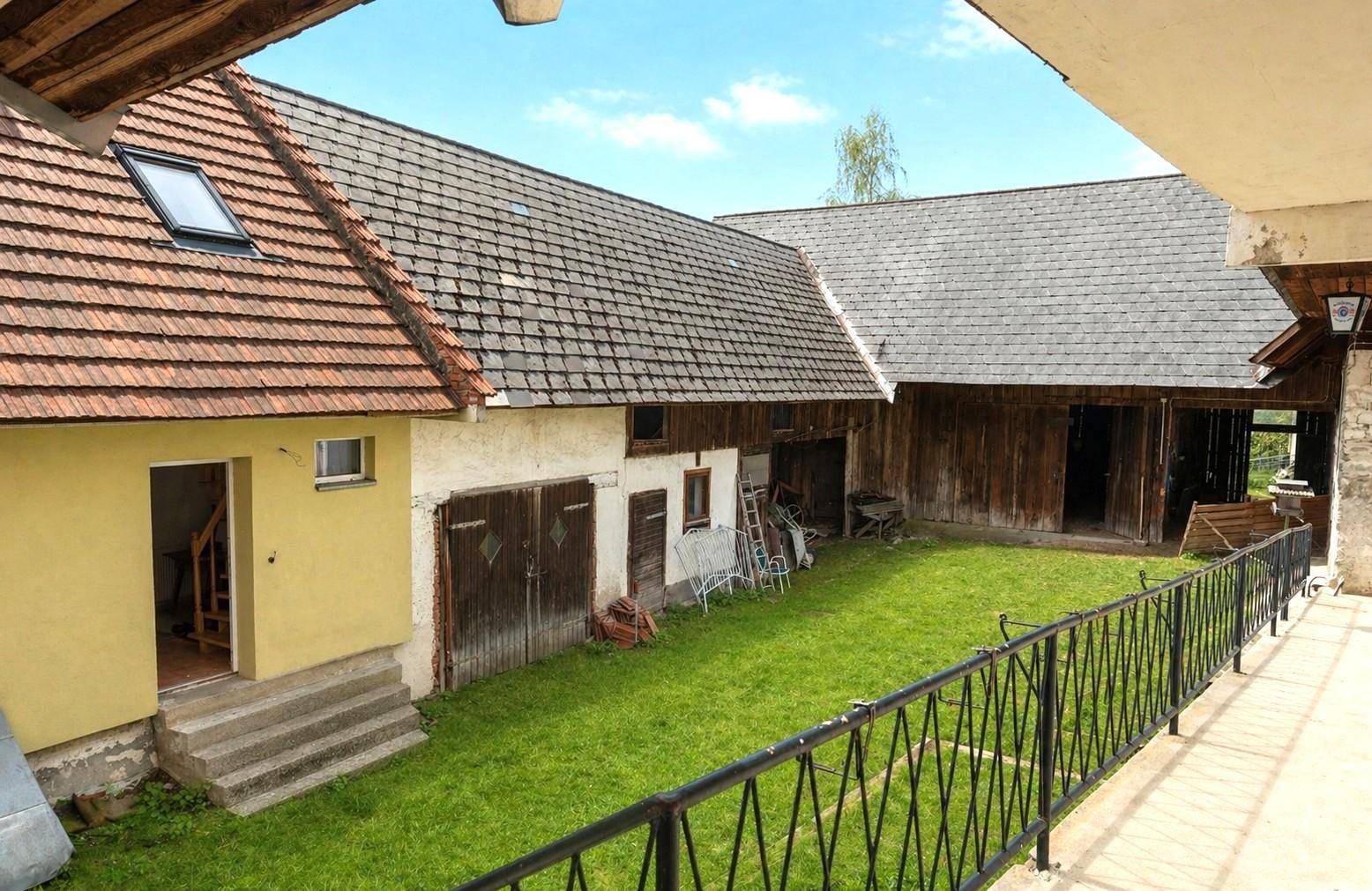 Blick von oben auf einen grünen Innenhof mit Rasenfläche und rustikalen Gebäuden.