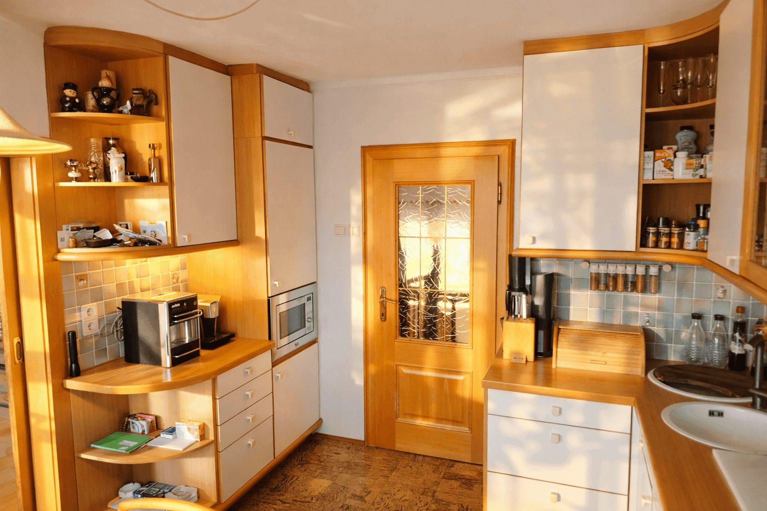 Funktionale Küche mit hellen Holzschränken, weißen Geräten und gefliester Rückwand.