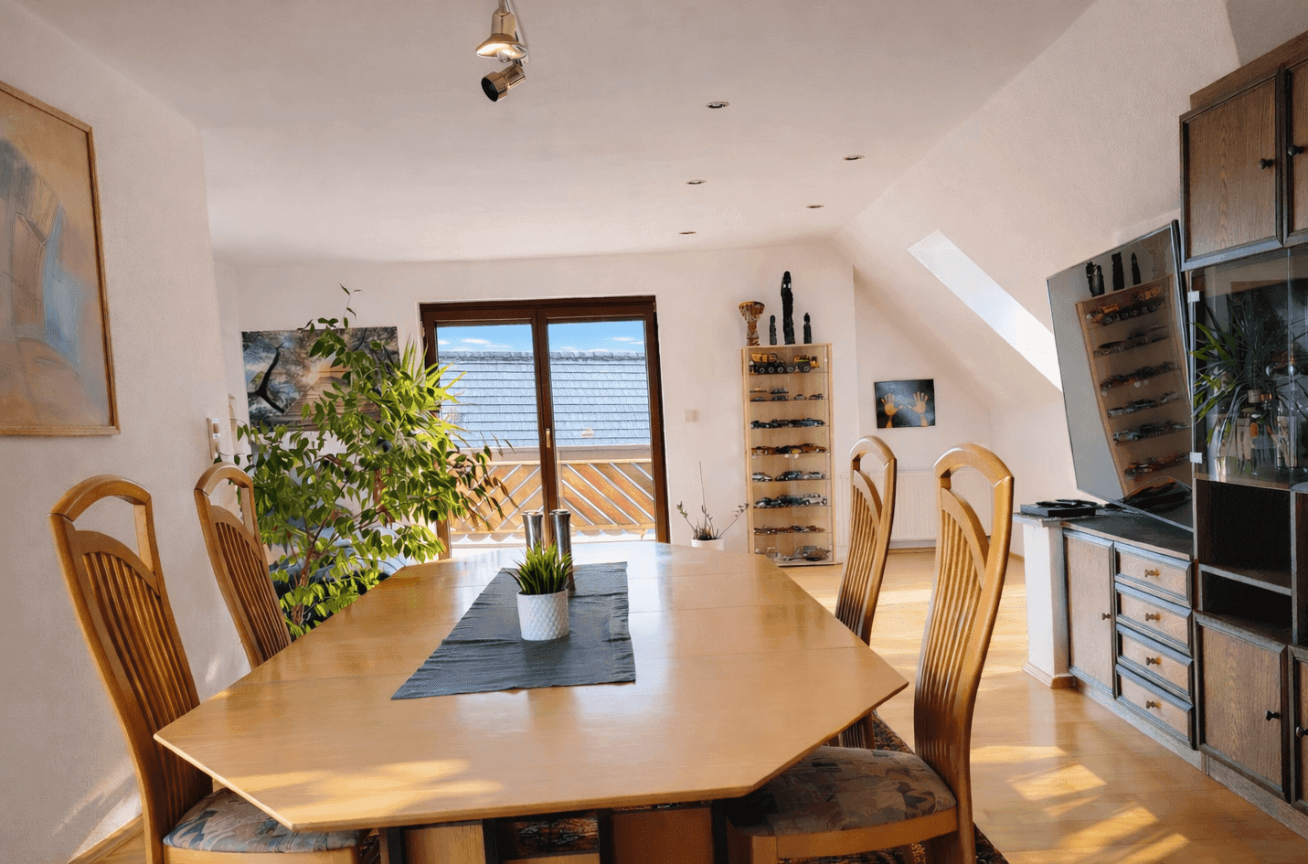 Helles Esszimmer im Dachgeschoss mit großem Holztisch, Stühlen und Balkonzugang.