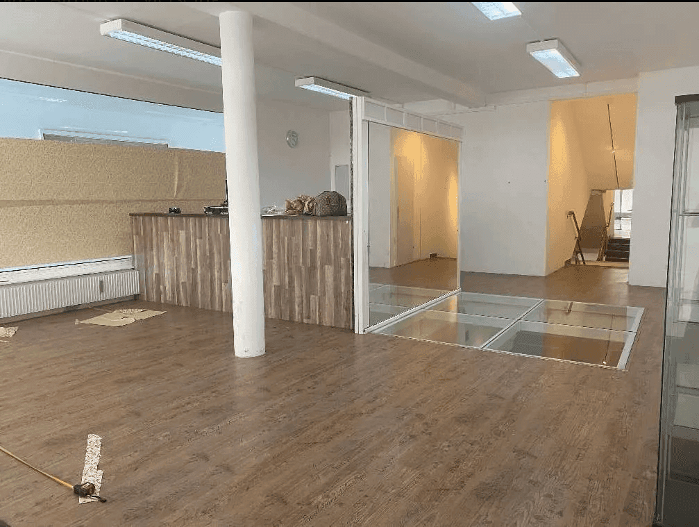 Großer Geschäftsraum mit Holzboden, einem Holztresen und interessanten Glasbodenelementen.