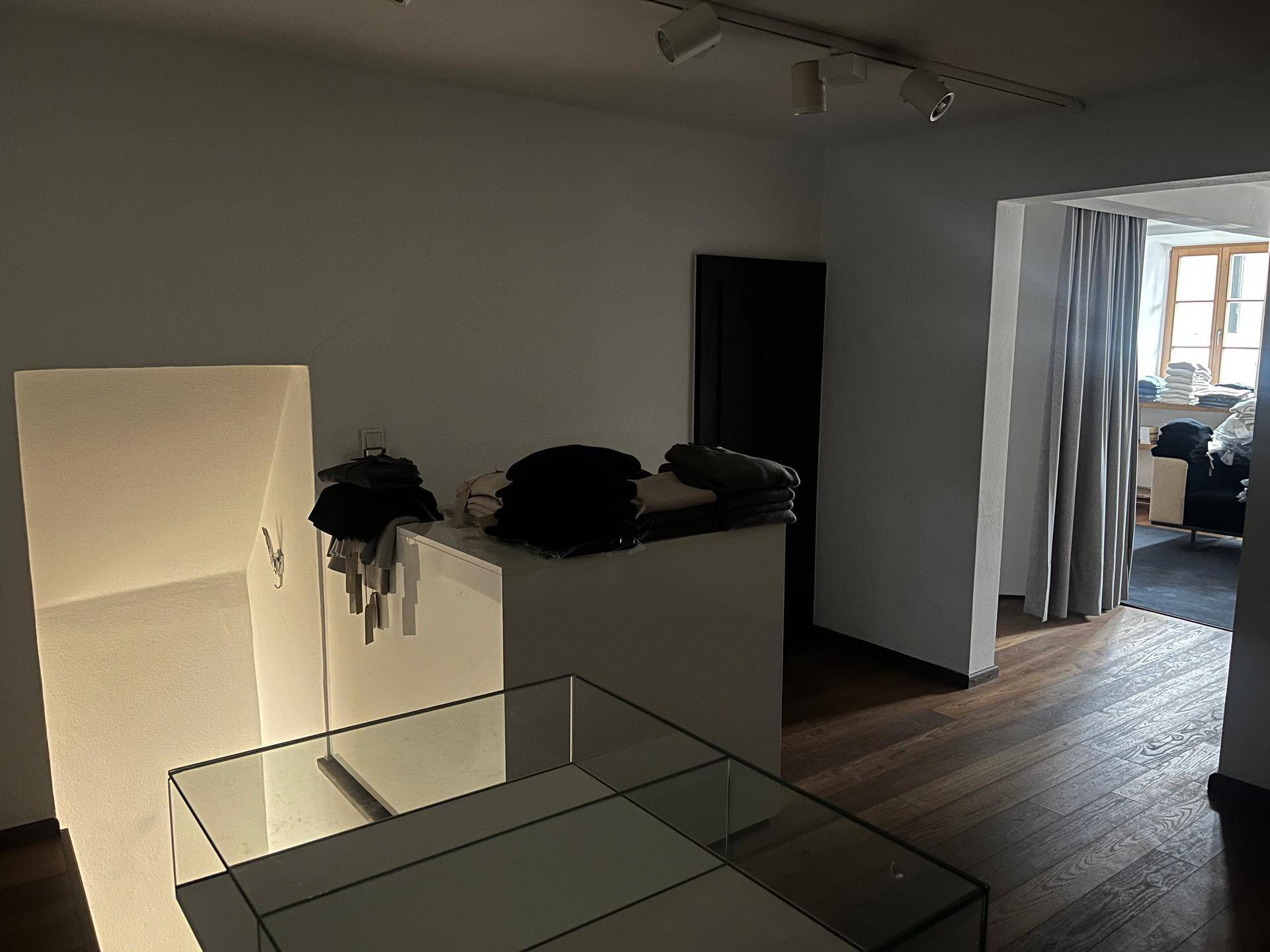 Obergeschoss eines Ladenlokals mit Holzboden, einem Glasdisplay und einem Blick in einen Nebenraum.