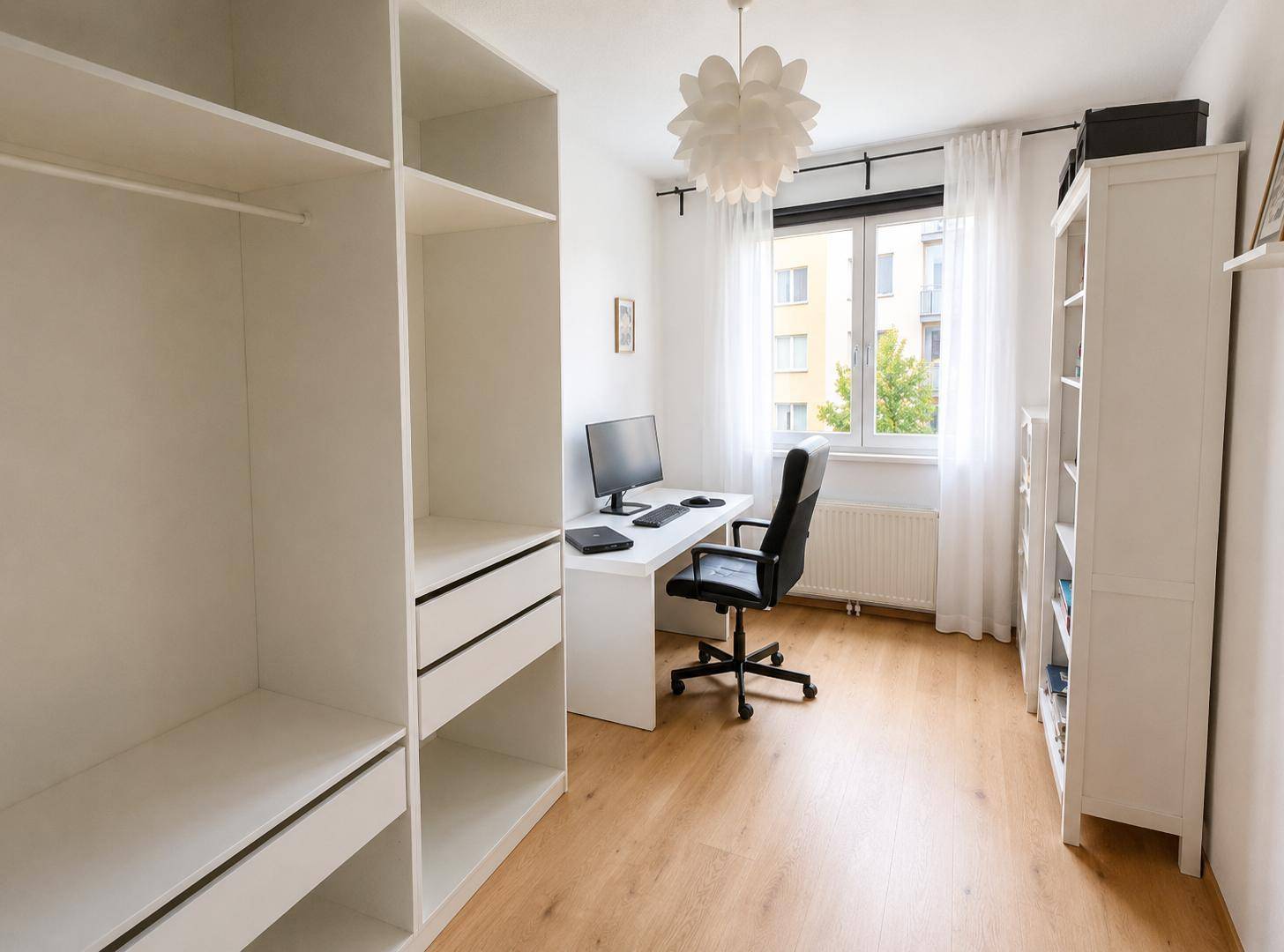Helles Arbeitszimmer mit Schreibtisch, Bürostuhl und integrierten Regalen.