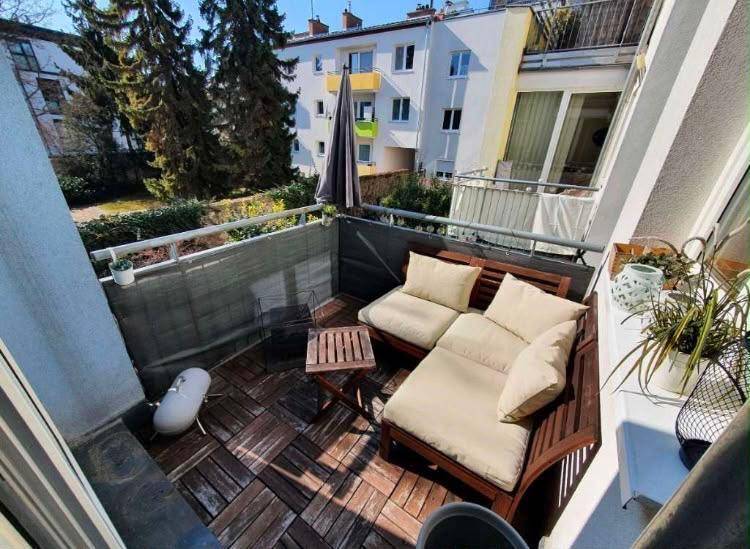 Gemütlicher Balkon mit Holzboden, Sitzmöbeln und Blick auf die Umgebung.