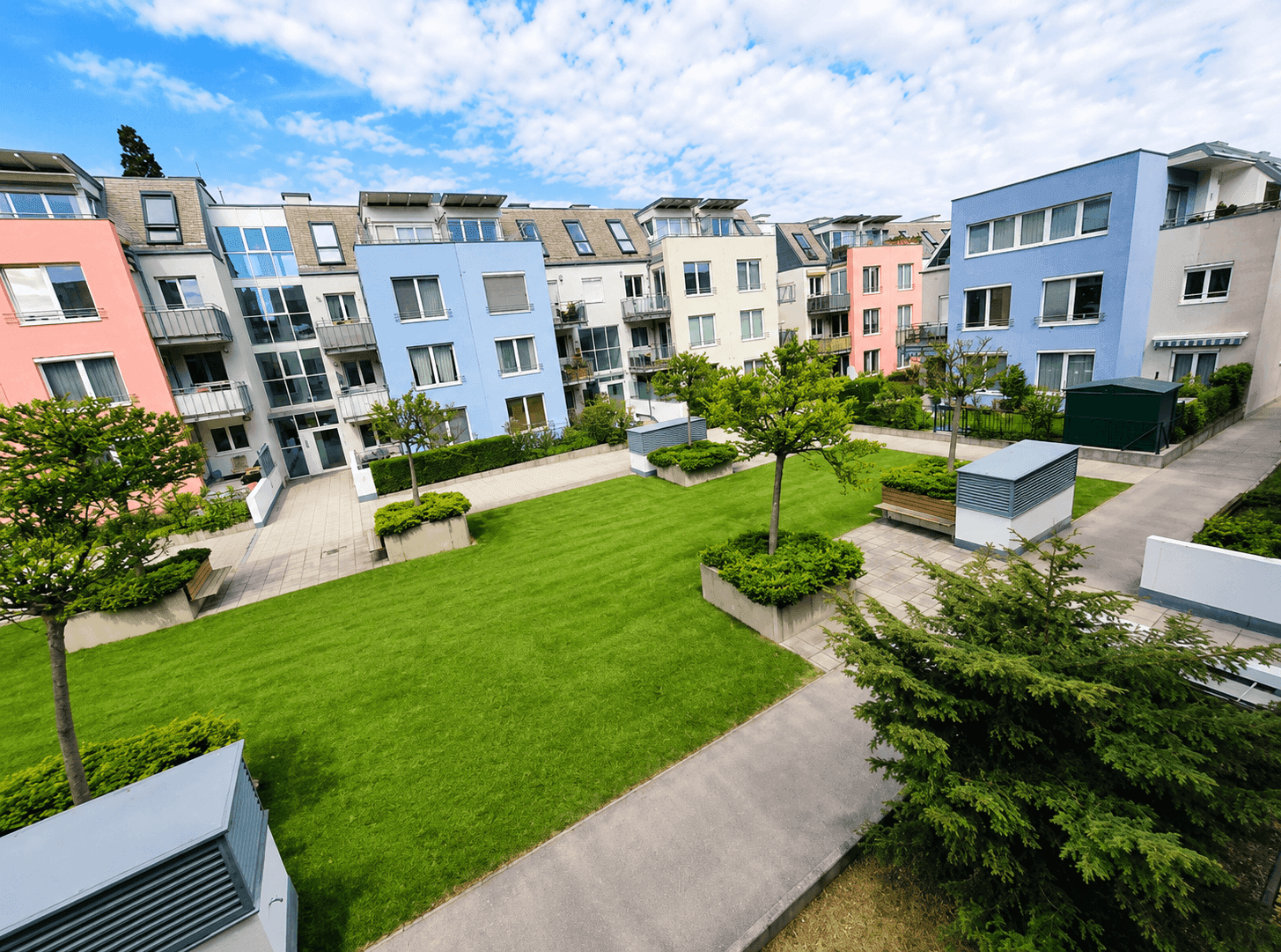 Innenhof mit gepflegter Rasenfläche und modernen Wohngebäuden in verschiedenen Farben.