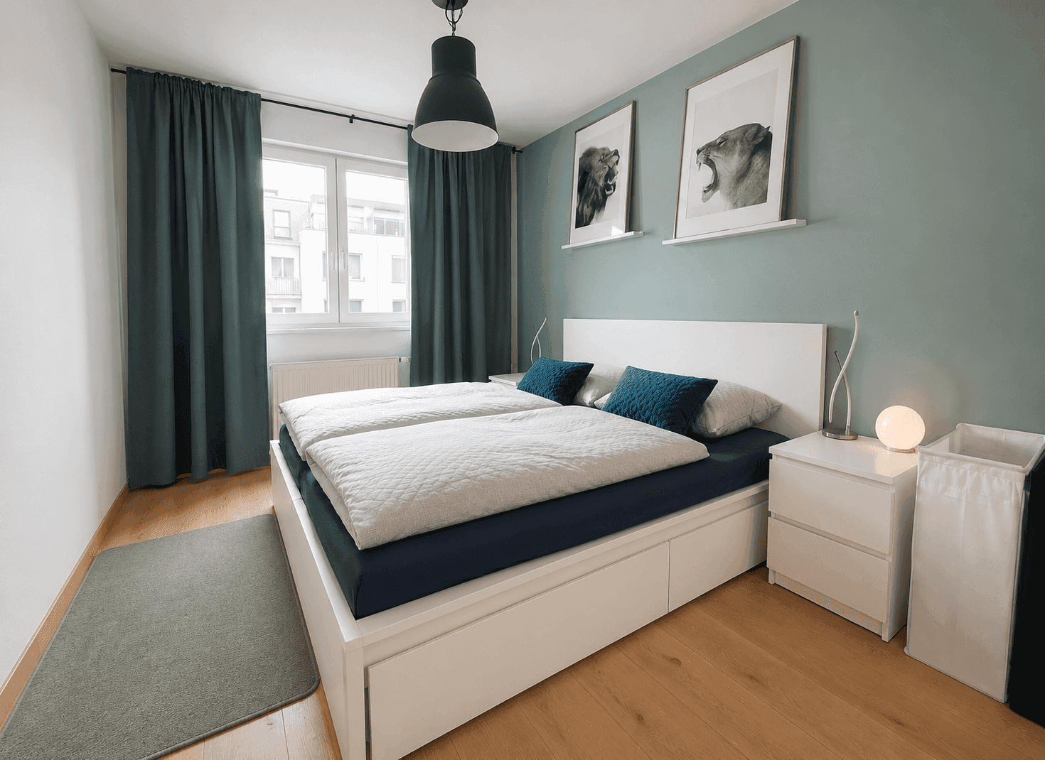 Modernes Schlafzimmer mit Doppelbett, Holzboden und teal-farbenen Akzenten.
