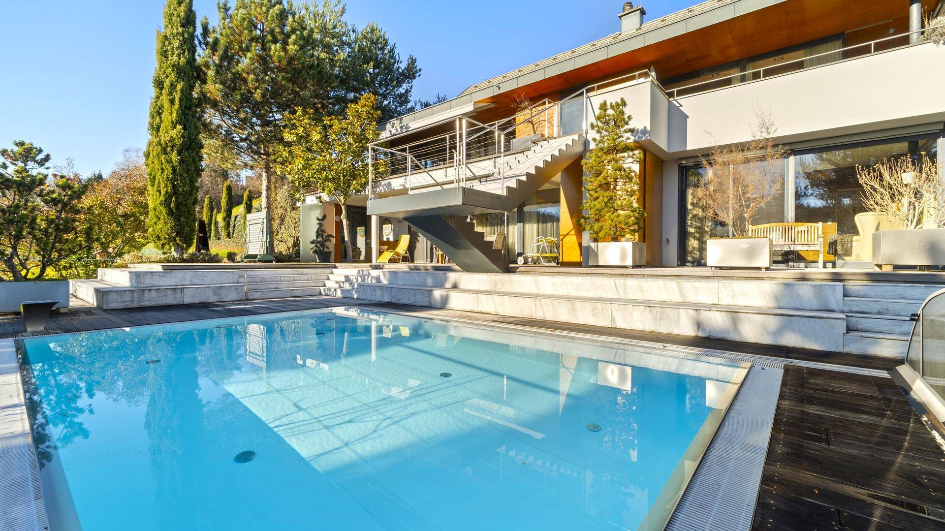Großzügiger Poolbereich mit Holzdeck und moderner Architektur des Hauses.