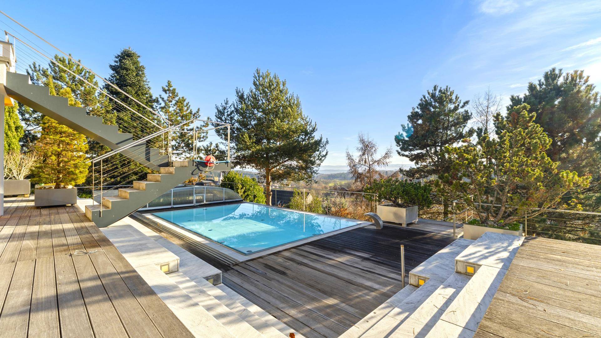 Außenbereich mit Pool, Holzdeck und Treppe zum oberen Stockwerk.