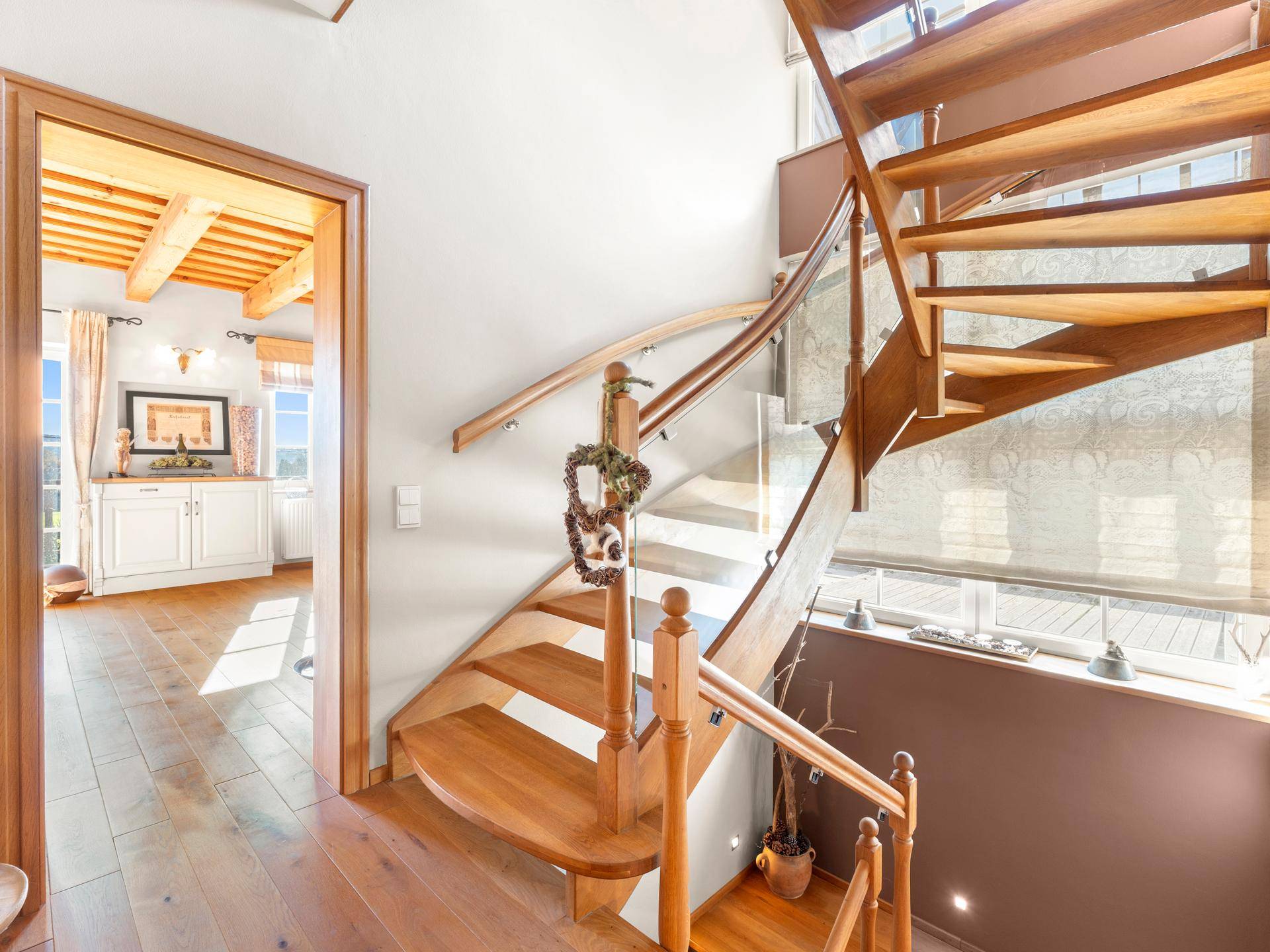 Elegante Holztreppe mit Glasgeländer, die die verschiedenen Ebenen des Hauses verbindet.