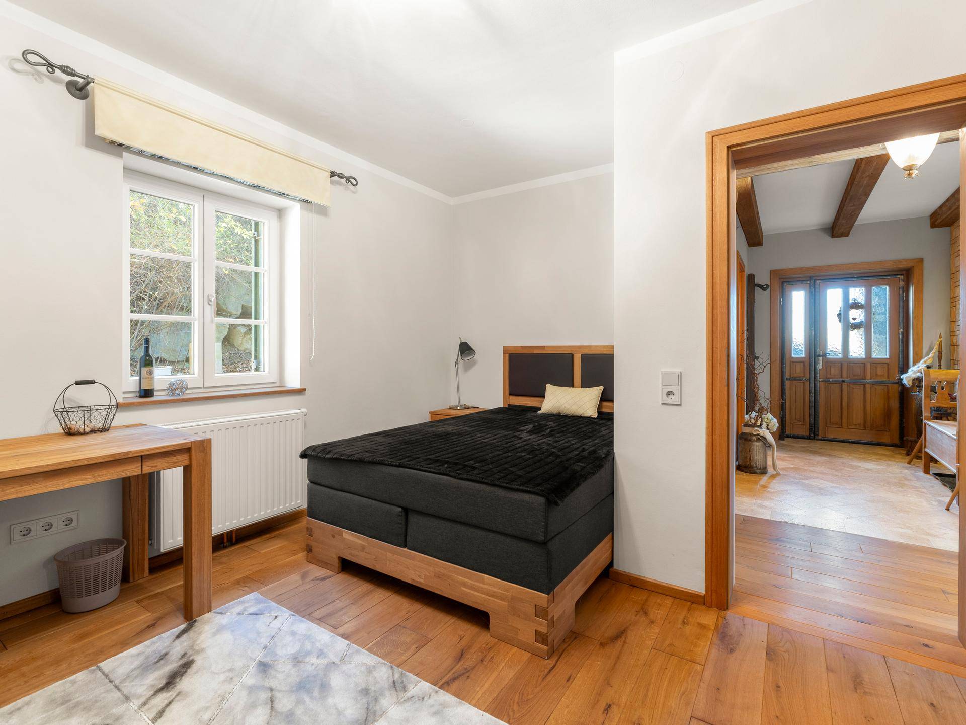 Helles Schlafzimmer mit Holzboden und Blick in den charmanten Eingangsbereich.