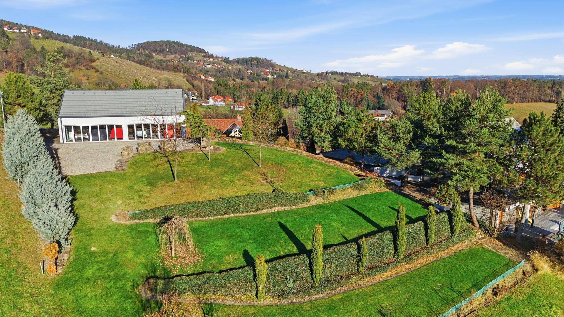 Weitläufige Außenansicht des modernen Anwesens mit gepflegten Rasenterrassen und Fernblick über die Landschaft.
