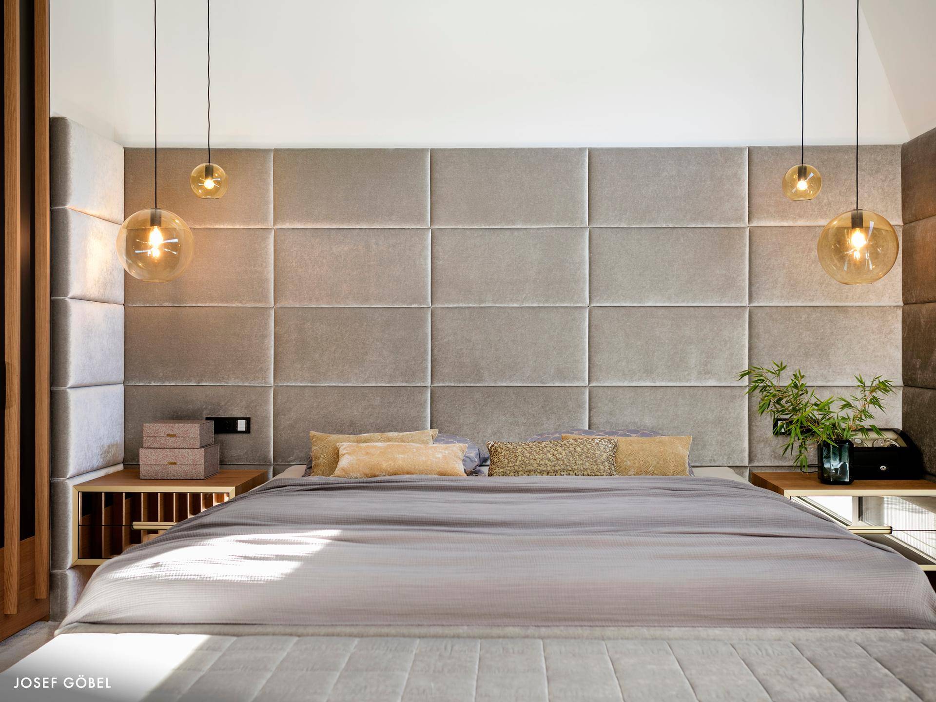 Modernes Schlafzimmer mit gepolstertem Kopfteil, stilvollen Nachttischen und indirekter Beleuchtung.