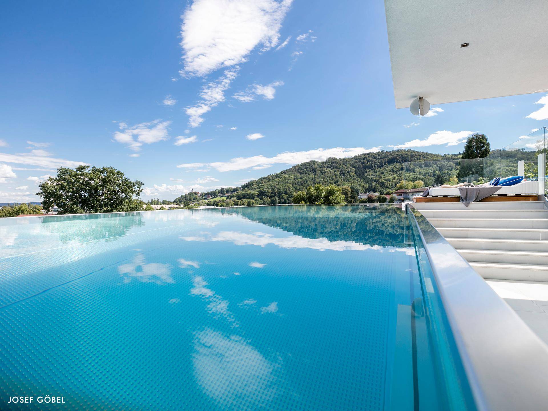 Atemberaubender Infinity-Pool mit klarem Wasser und weitem Blick über die grüne Hügellandschaft.