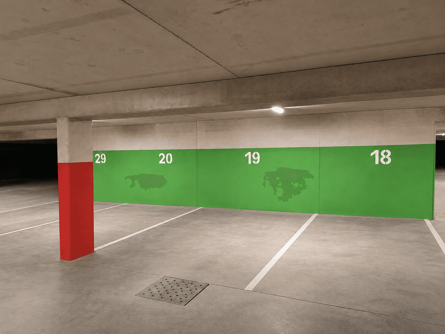 Tiefgaragenstellplatz mit grüner Wand und roter Säule in einer sauberen und modernen Parkanlage.