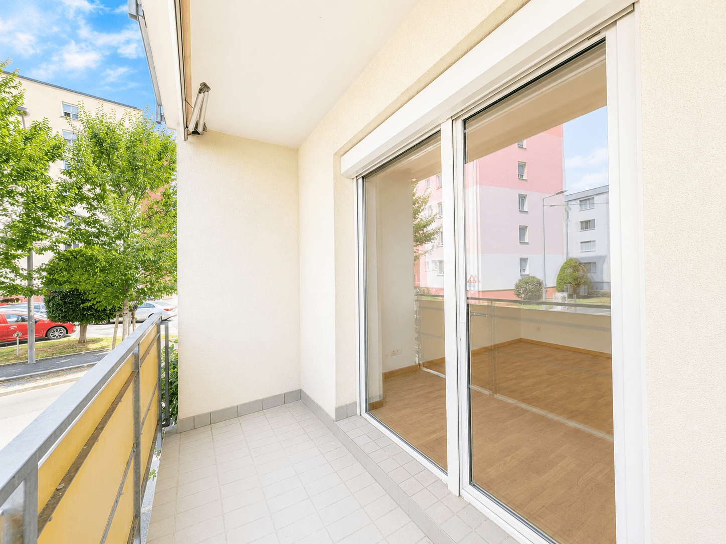 Heller Balkon mit Fliesenboden und Blick auf die Umgebung, ausgestattet mit Rollläden.
