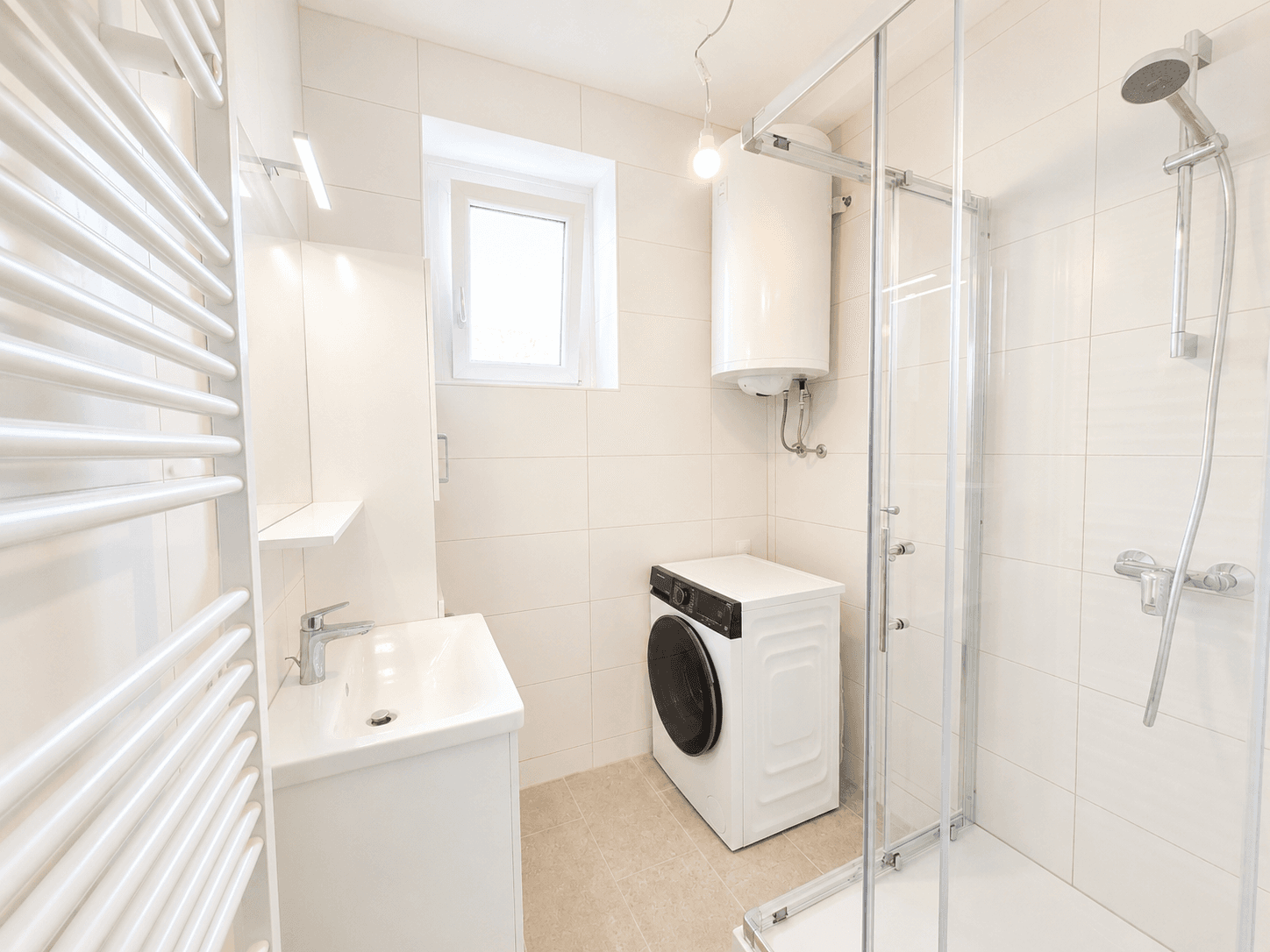 Modernes Badezimmer mit Dusche, Waschbecken und Waschmaschine, hell gefliest und mit Fenster.