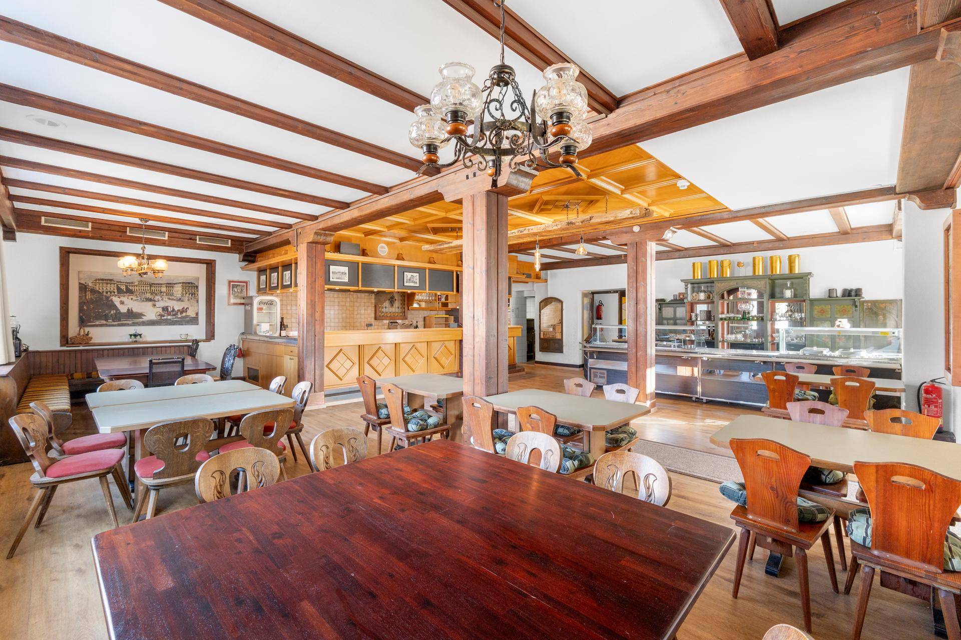 Traditioneller Speisesaal mit Holzbalkendecke, rustikalen Möbeln und Buffetbereich für Gäste.