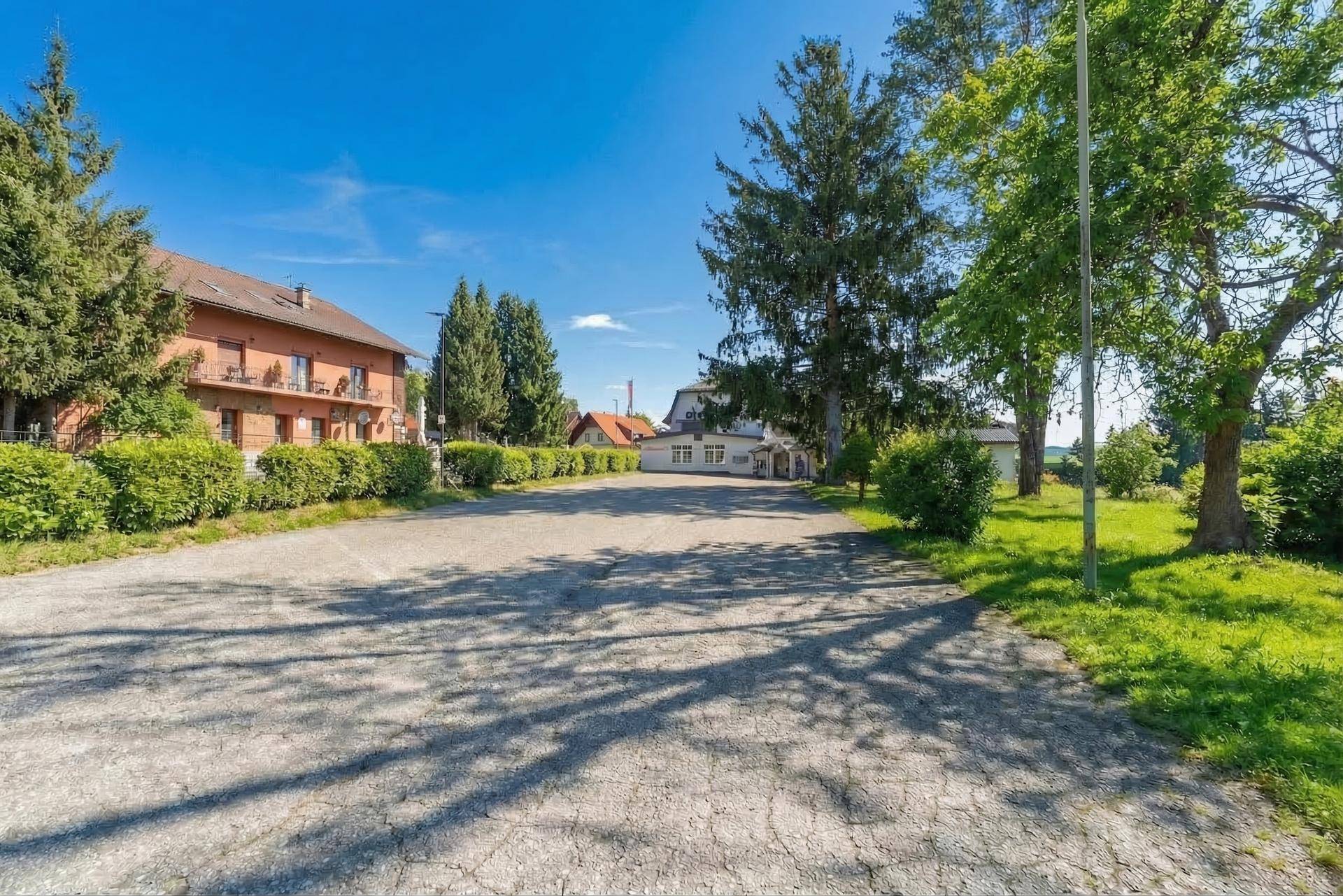 Großer Schotterparkplatz mit ausreichend Stellflächen für Fahrzeuge vor den Gebäuden.