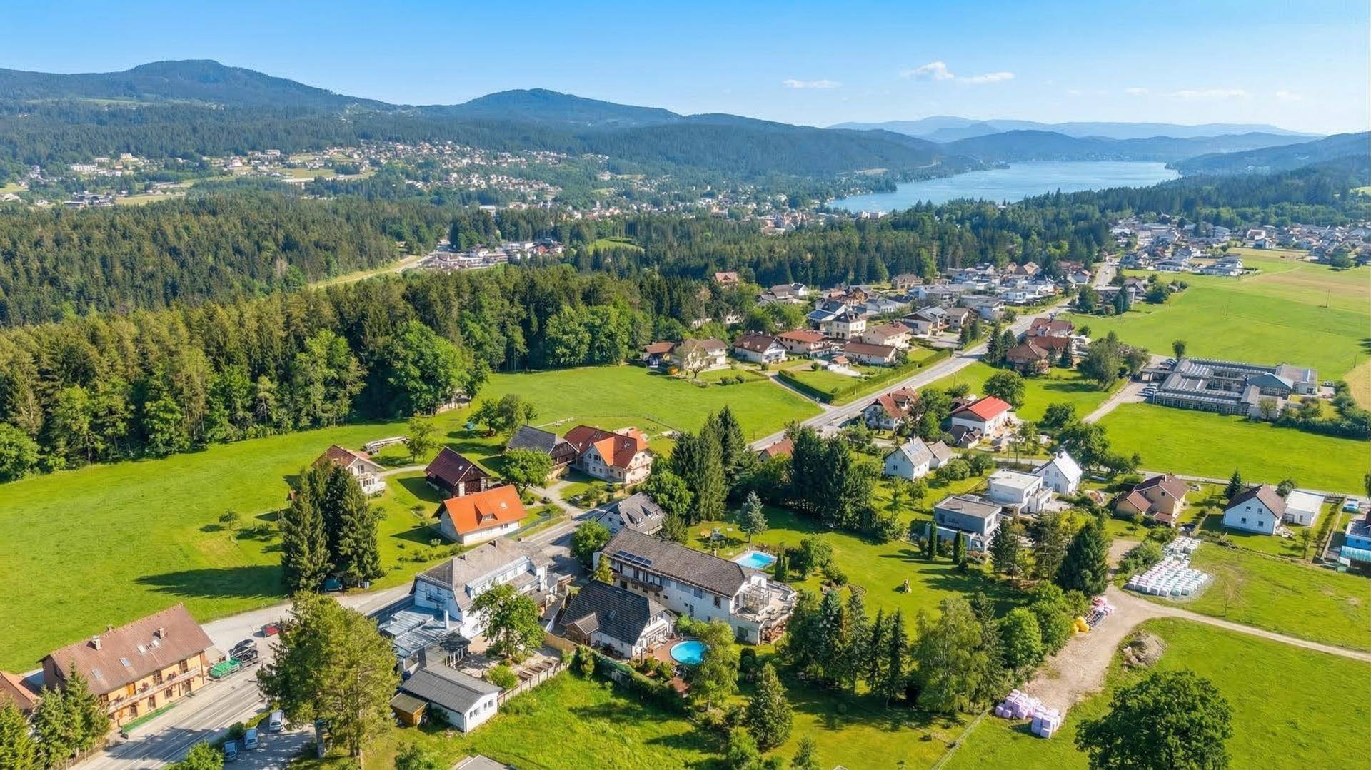 Panoramablick auf die ländliche Umgebung mit einem See, Wäldern und einer kleinen Ortschaft.