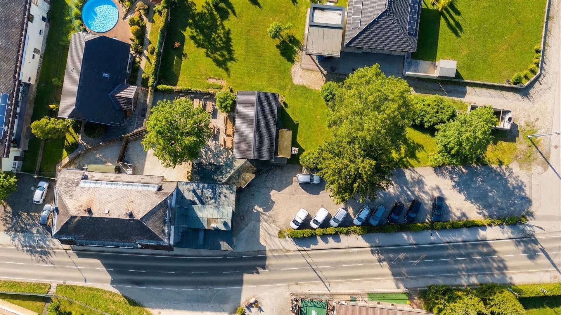 Senkrechte Luftaufnahme des Anwesens mit Parkplätzen, angrenzendem Pool und Grünflächen.