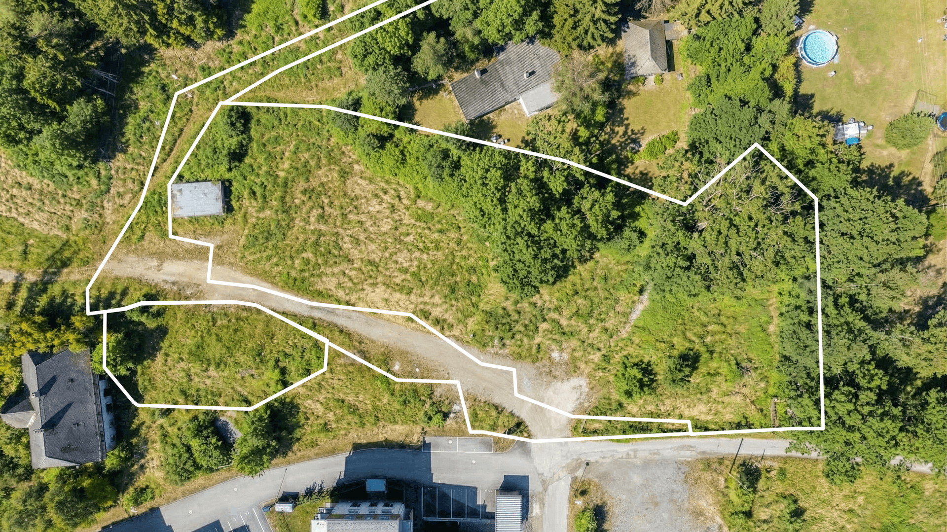 Draufsicht auf ein großes, unregelmäßig geformtes Grundstück mit weißer Umrandung und angrenzender Straße.